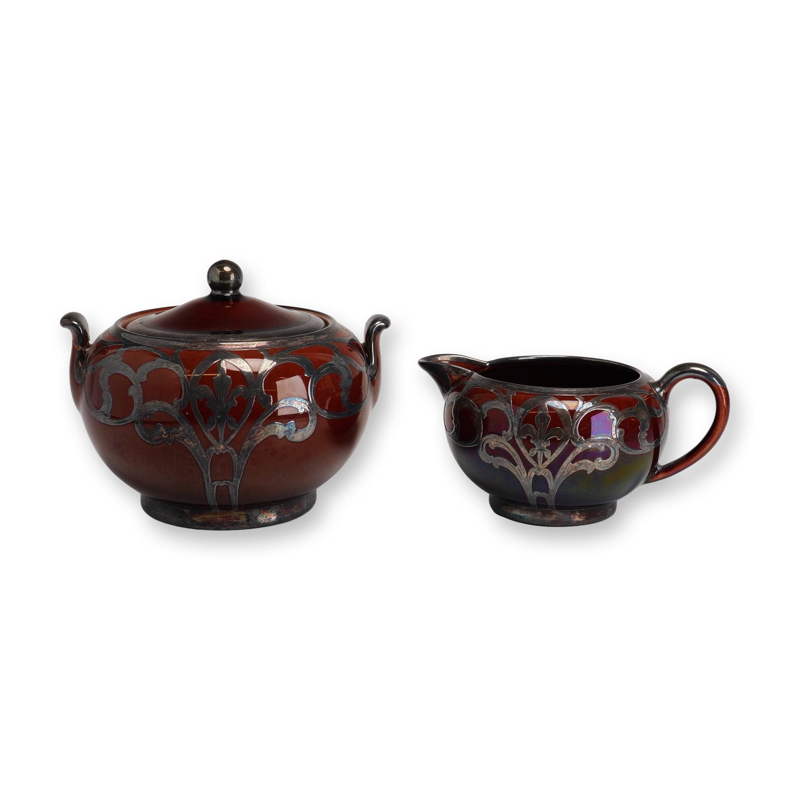 2pc Wedgwood Silver Overlay Lidded Sugar and Creamer Jug: This two-piece ceramic tea service includes a lidded sugar bowl and a creamer jug, both featuring intricate Art Nouveau silver overlay decoration. The set is finished in a deep, high-gloss mahogany br
