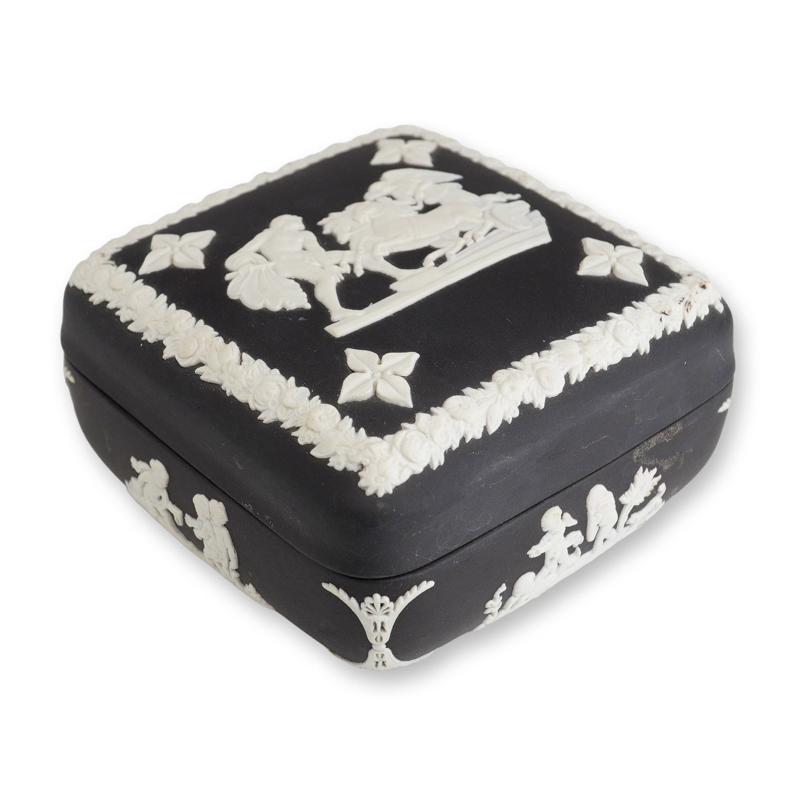 Wedgwood Black Jasperware Lidded Trinket Box: A Wedgwood black jasperware square-form lidded trinket box featuring white bas-relief sprigged decoration in the neoclassical style. The object is composed of unglazed matte black stoneware. The sligh
