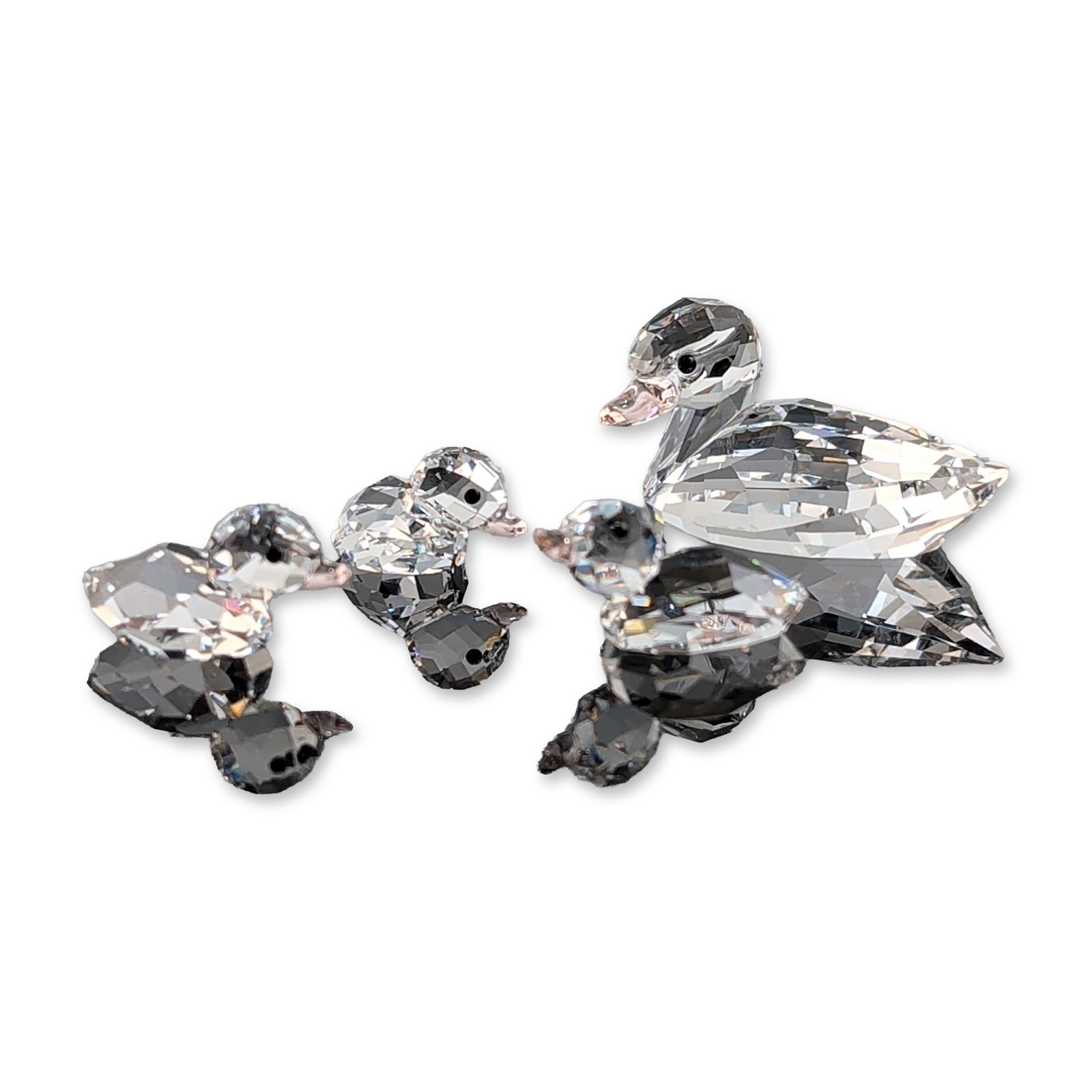 Swarovski Crystal Duck Family Figurine Set: A group of figurines in faceted lead crystal from the Peaceful Countryside collection, featuring a mother duck followed by three ducklings. Each piece is constructed from clear faceted crystal and det