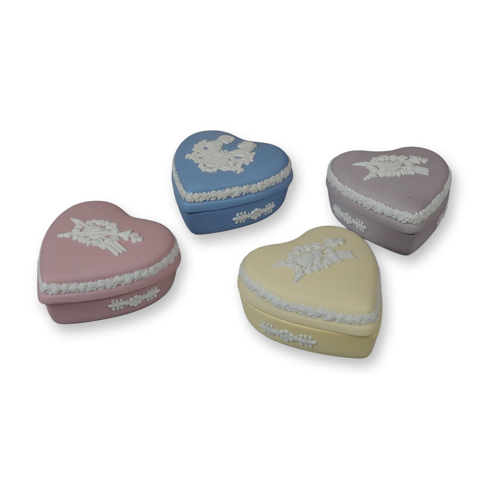 4pc Wedgwood Jasperware Heart-Shaped Trinket Boxes: A collection of four heart-shaped Jasperware stoneware trinket boxes produced by Wedgwood, England. The group includes examples in pink, pale blue, primrose yellow, and lilac, each finished in the cla