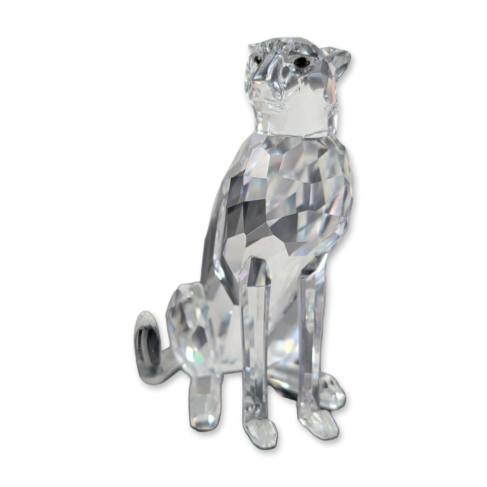 Swarovski Faceted Crystal Seated Cheetah: Swarovski faceted clear crystal figurine of a seated cheetah from the African Wildlife collection. The piece features a multi-faceted body with a smooth curved tail and dark-colored eyes. The cheetah 