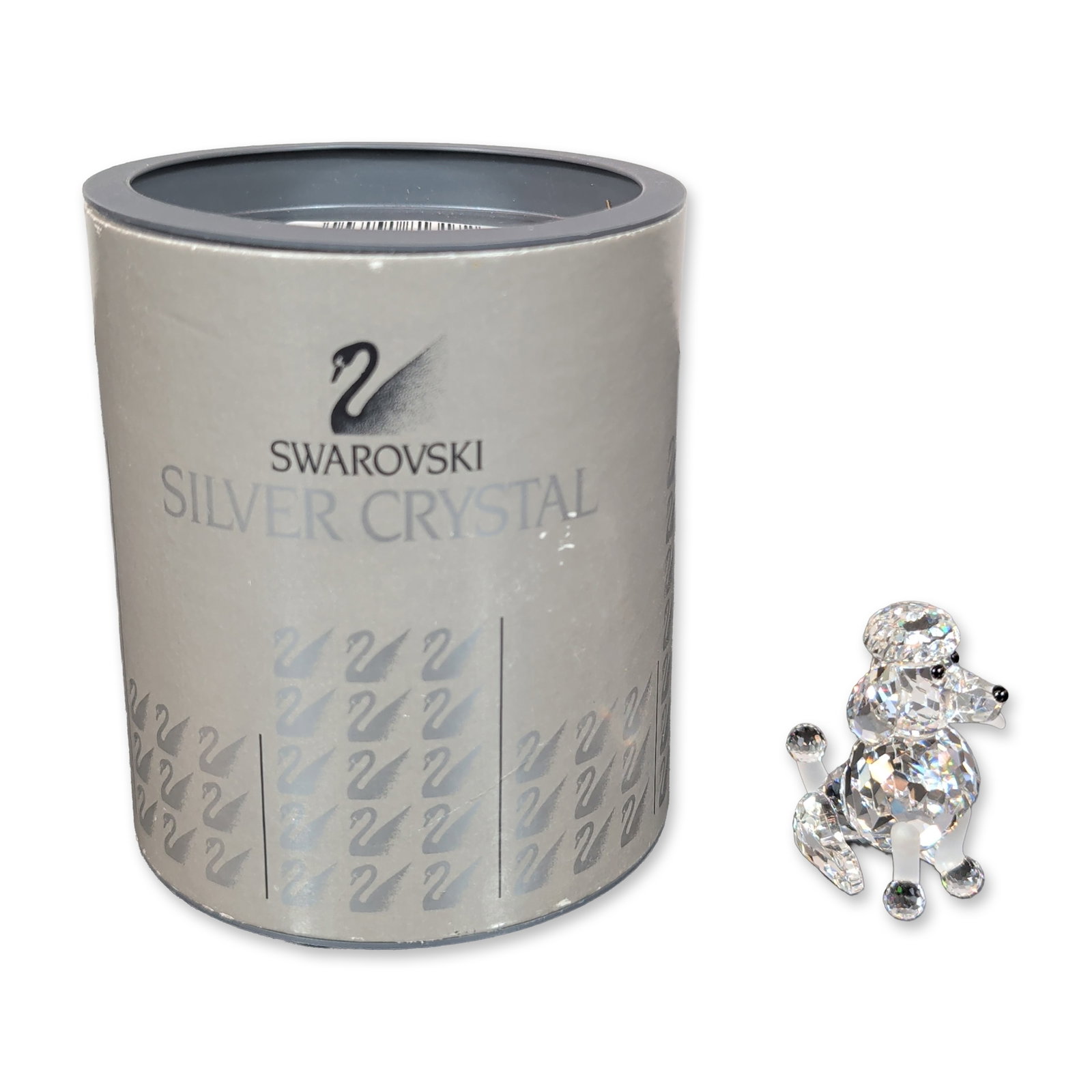 Swarovski Silver Crystal Sitting Poodle Figurine: Swarovski Silver Crystal seated poodle figurine in faceted and frosted lead crystal. The piece features a show cut design with a faceted body and head, frosted accents to the legs and tail, and black 