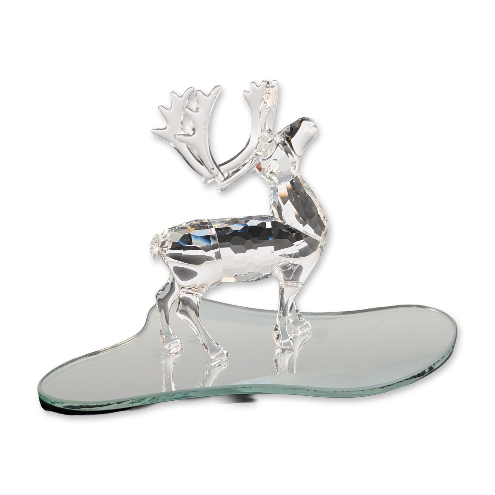 Swarovski Silver Crystal Reindeer Figurine with Mirror Base: Swarovski Silver Crystal faceted clear crystal reindeer figurine. The piece features a multi-faceted body with branching antlers and is accompanied by an irregular shaped mirrored glass display base. 