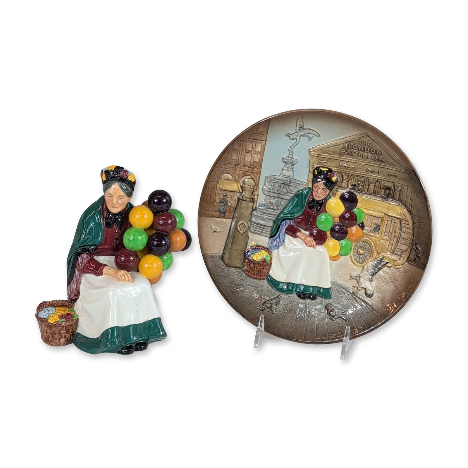 2pc Royal Doulton Old Balloon Seller Porcelain Figurine HN1315 & Plate: Royal Doulton porcelain group featuring the Old Balloon Seller motif, including one three-dimensional figurine and one coordinating bas-relief collector plate. The figurine depicts a seated elderly wo