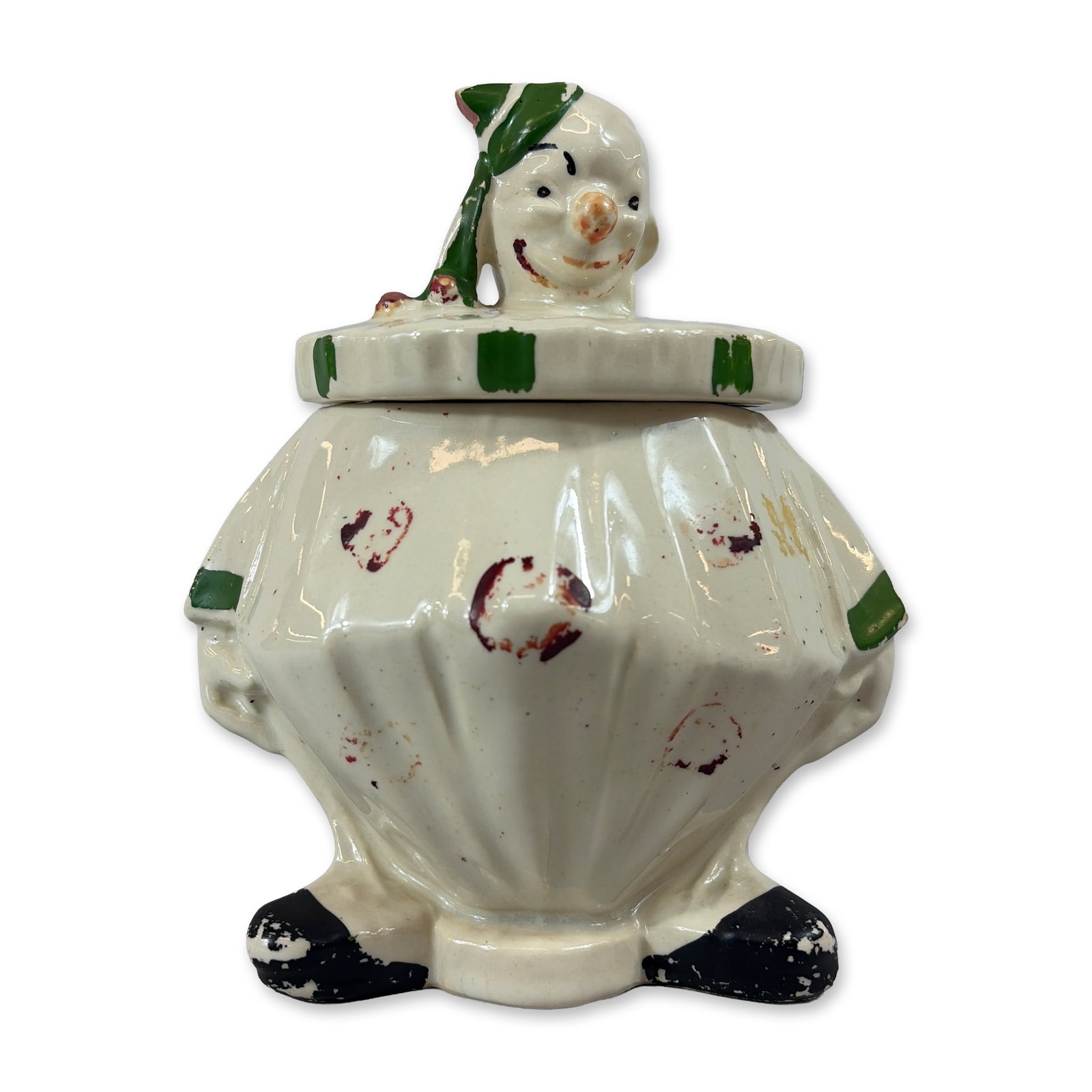 McCoy Painted Ceramic Clown Cookie Jar: Formed as a seated clown figure in glazed earthenware, featuring a large, ruffled collar and pointed cap. The costume is embellished with cold-painted accents in green, black, and red. The lid consist