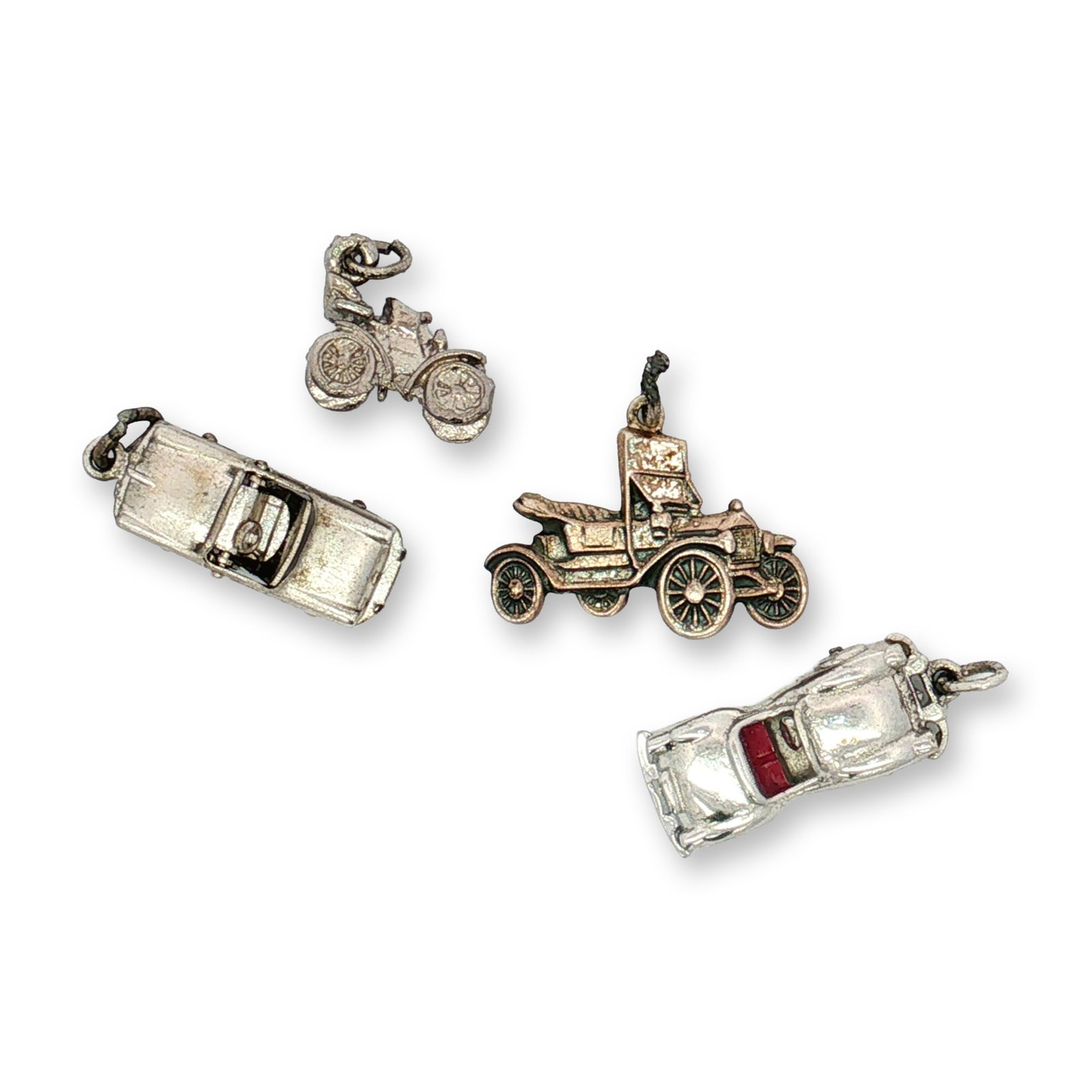 4pc Sterling and Non-Sterling Silver Vintage Cars Charms: A collection of miniature silver charms modeled after cars, including two convertibles, and a Model T. One charm is marked Sterling. Dimensions: 1"L x 0.5"H Weight: 14.33 g