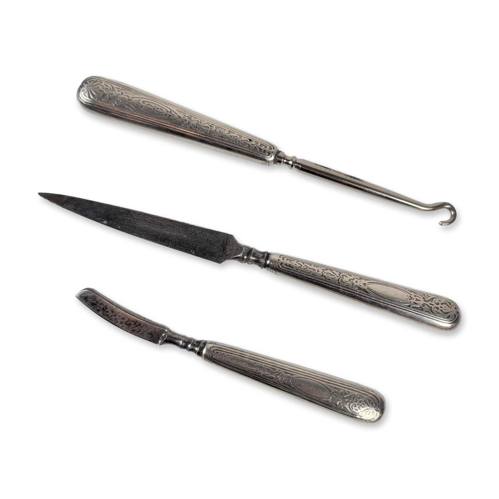 Three-Piece Albany NY Sterling Silver Manicure Set: Late 19th or early 20th century American manicure set. Three pieces featuring sterling silver handles with steel functional components, including a button hook, a nail file, and a curved razor. The ha