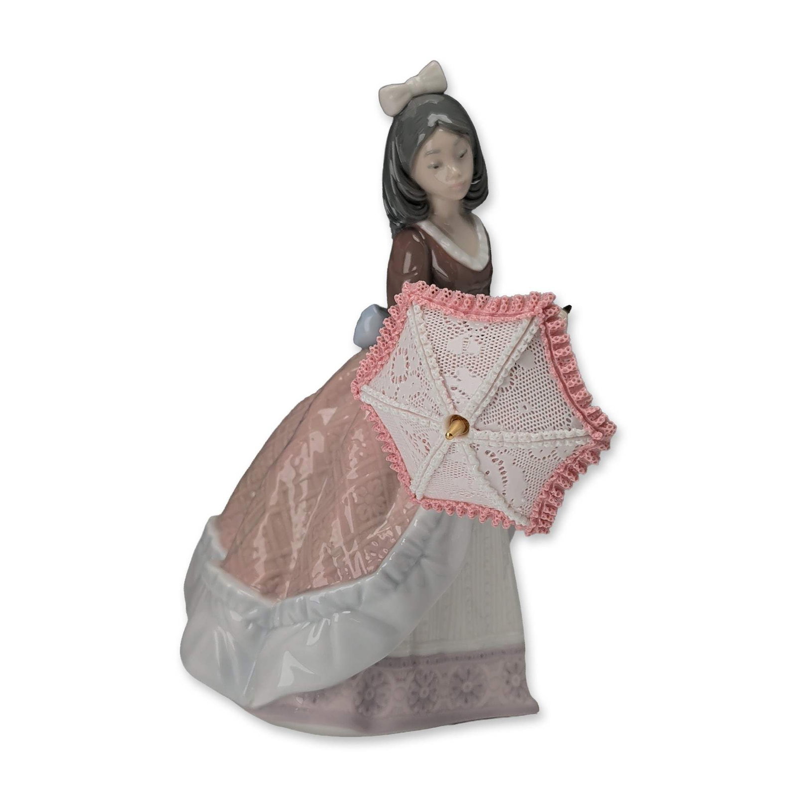 Lladro Jolie Porcelain Lady Figurine 5210: Lladro glazed porcelain figurine titled Jolie, model number 5210. The piece depicts a young woman in a stylized Victorian-era dress featuring a brown bodice, light blue bow, and a multi-layered pink a