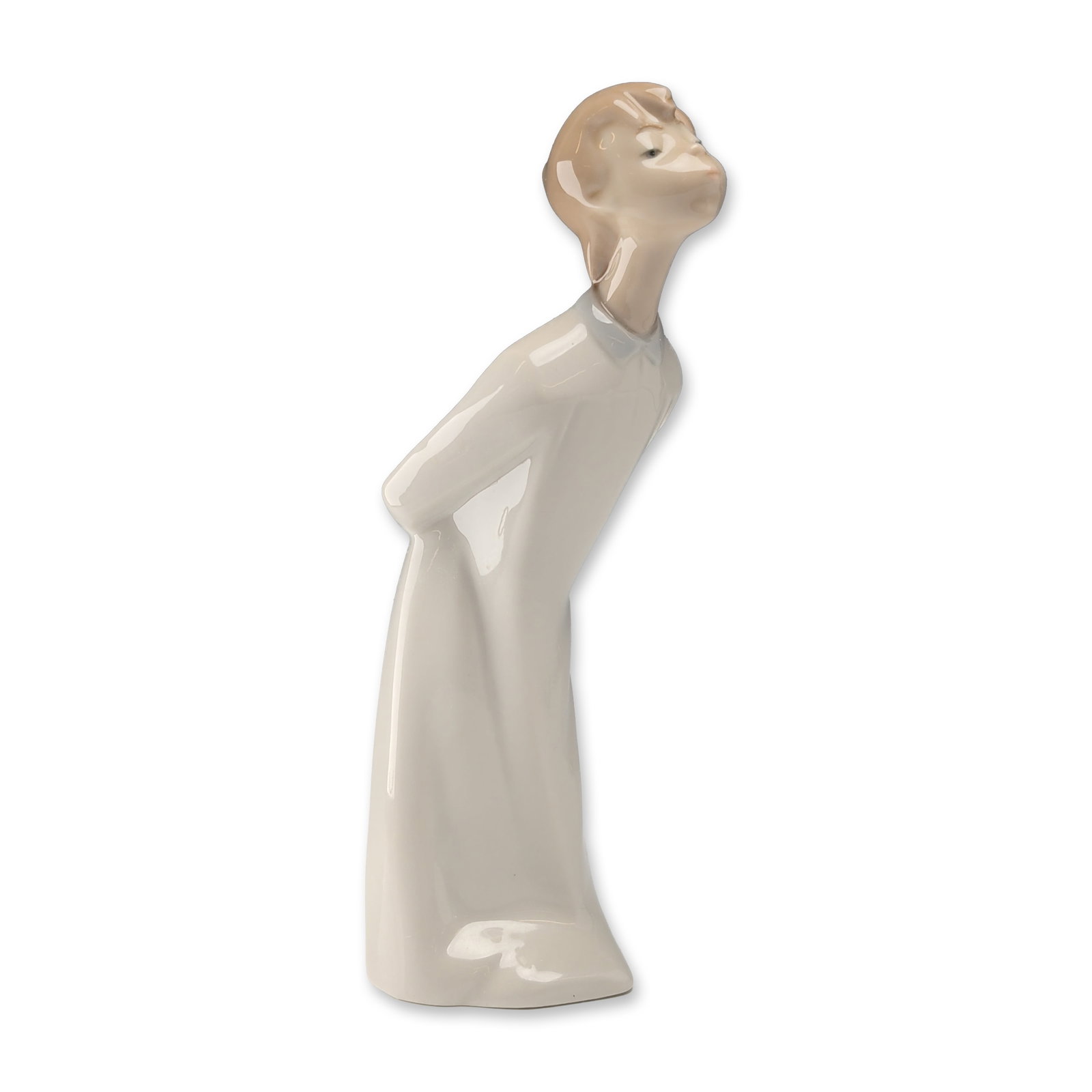 Lladro Spanish Porcelain Boy Kissing Figurine: Lladro, Spain. Glazed porcelain figurine depicting a young boy in a long cream-colored gown, leaning forward with hands tucked behind him. Minimalist design with elongated features and a high-gloss fi