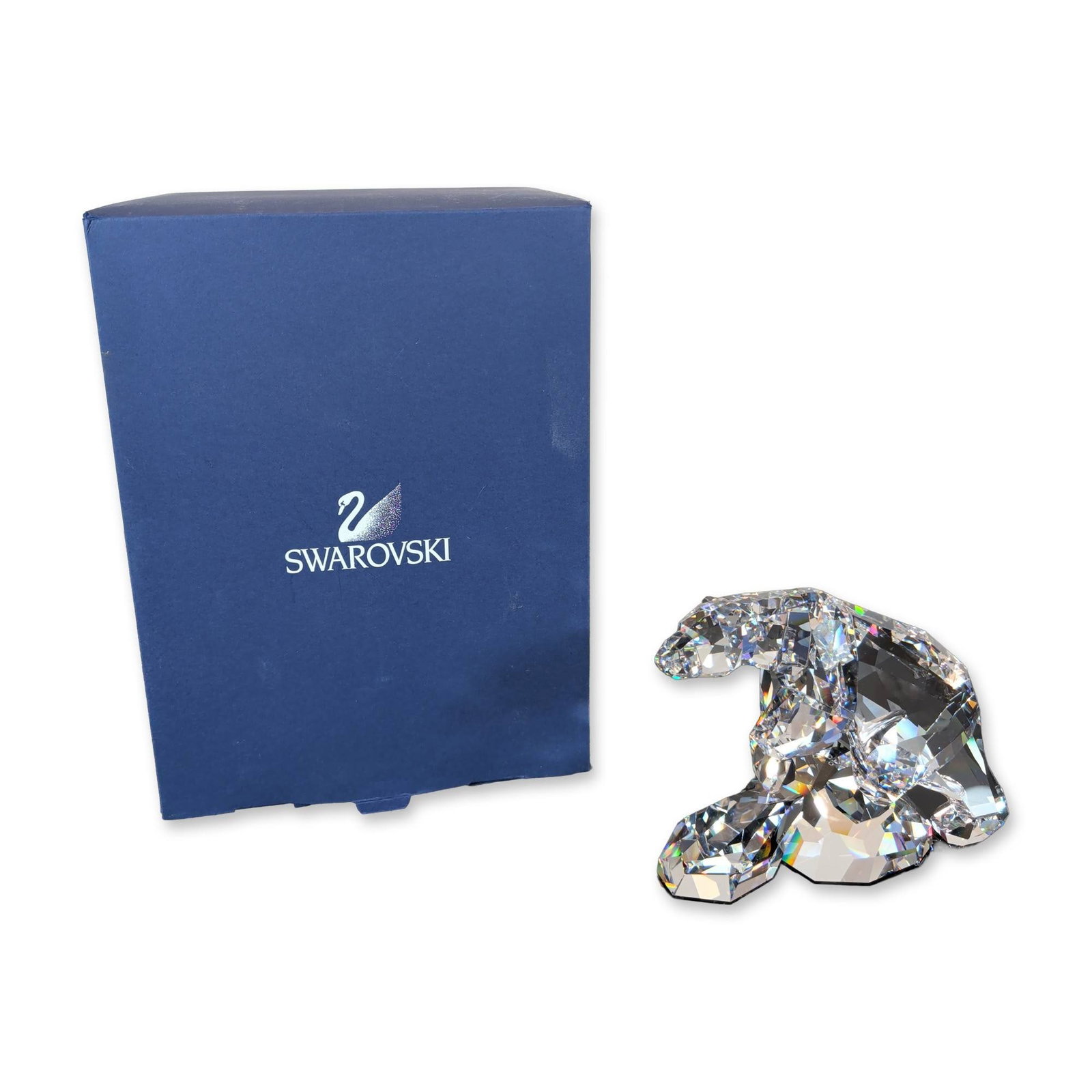 Swarovski Crystal Nanuc Polar Bear Figurine: Nanuc Polar Bear figurine in faceted clear lead crystal. The piece features numerous facets and an etched swan maker mark to the crystal. Accompanied by original blue Swarovski presentation box. Dimen