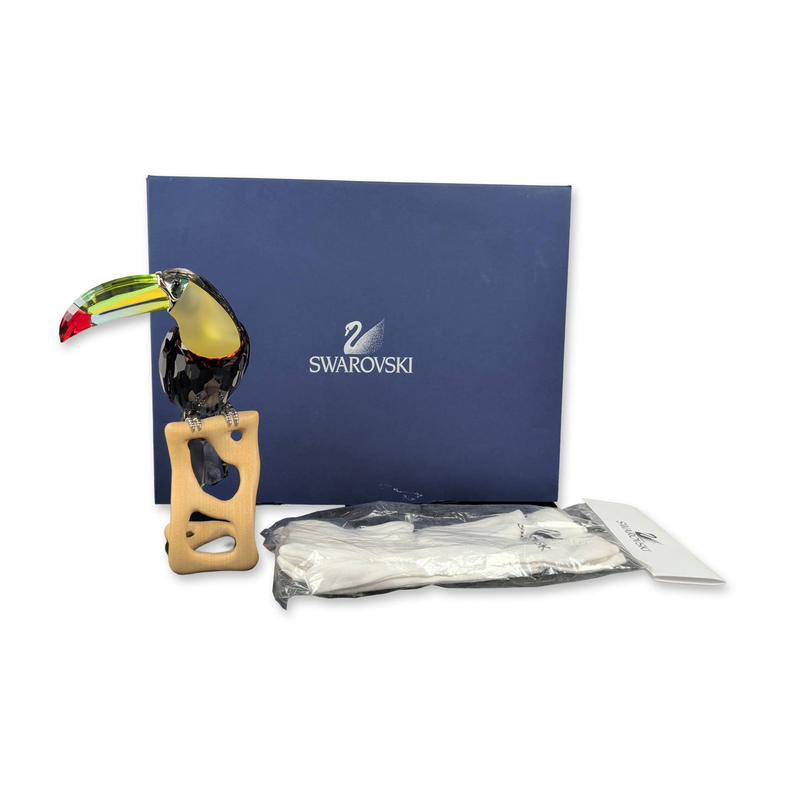 Swarovski Austrian Crystal Black Diamond Toucan Figurine: Swarovski Austrian faceted lead crystal figurine depicting a toucan, part of the Paradise collection. The bird features a Black Diamond crystal body, a multi-colored beak in shades of yellow, green, a
