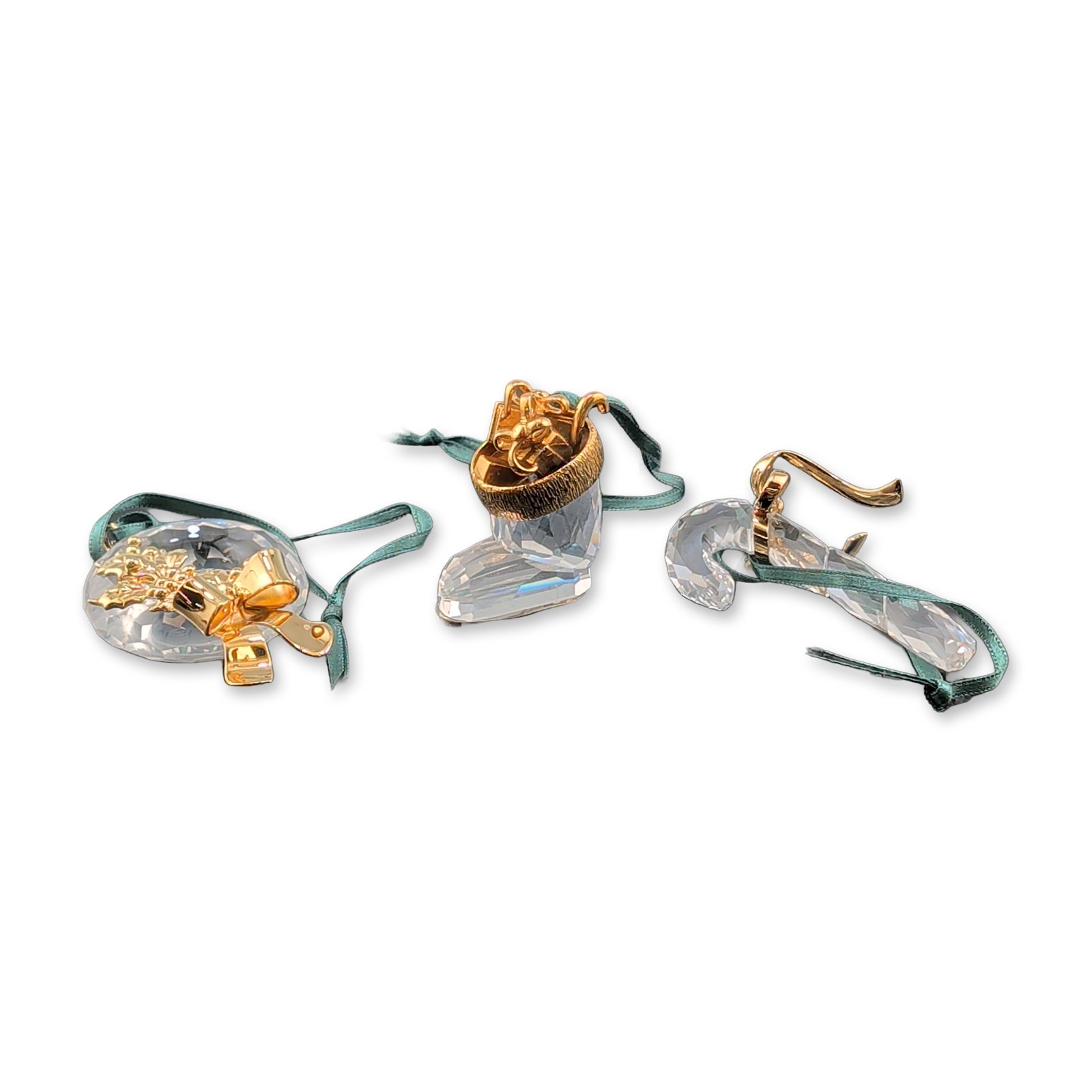 Trio of Swarovski Crystal Christmas Ornaments: Swarovski Christmas Memories collection of three hanging ornaments in faceted clear crystal with gold-tone metal accents, including a candy cane, a boot, and a circular wreath with a bow and evergreen
