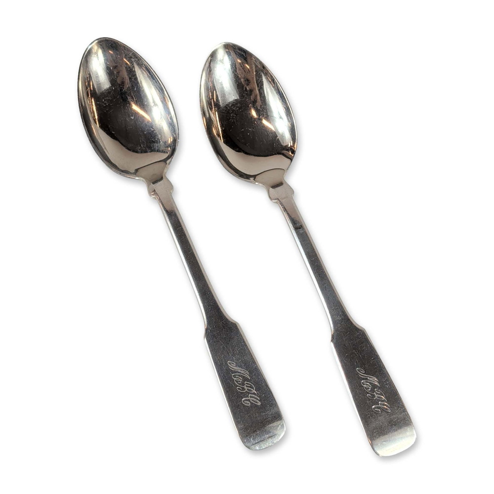 Pair of Sterling Silver Spoons: Pair of soup spoons in sterling silver, featuring a classic American Fiddle pattern with rounded handle ends. Each handle is hand-engraved on the front with the script monogram M B C. The reverse of t