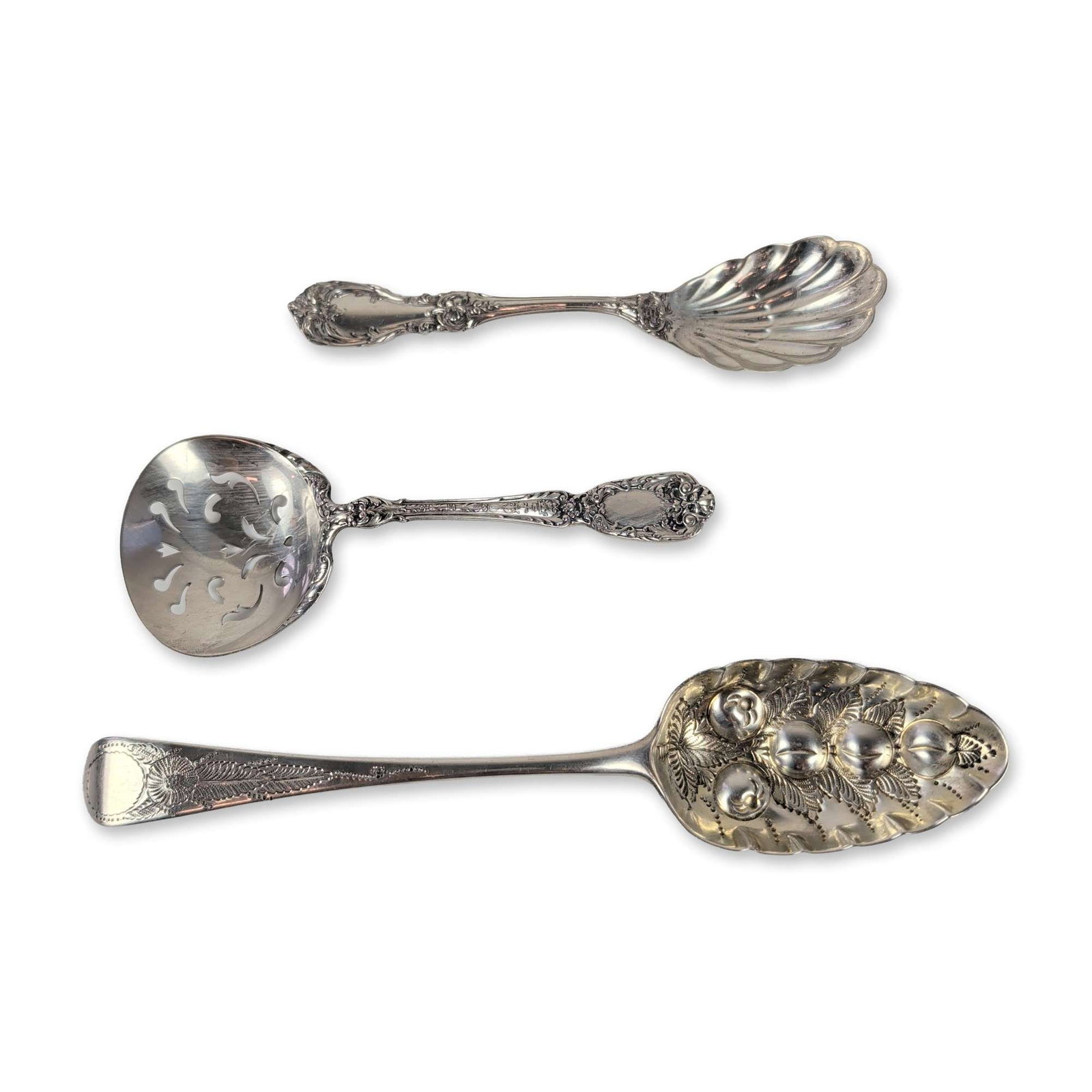 Three Sterling Silver Serving Spoons Including Reed and Barton: The set includes a shell-bowl nut or bon-bon spoon and a pierced sifter spoon, both adorned with ornate floral and fruit designs. The third piece is a George III English sterling silver berry spoon,