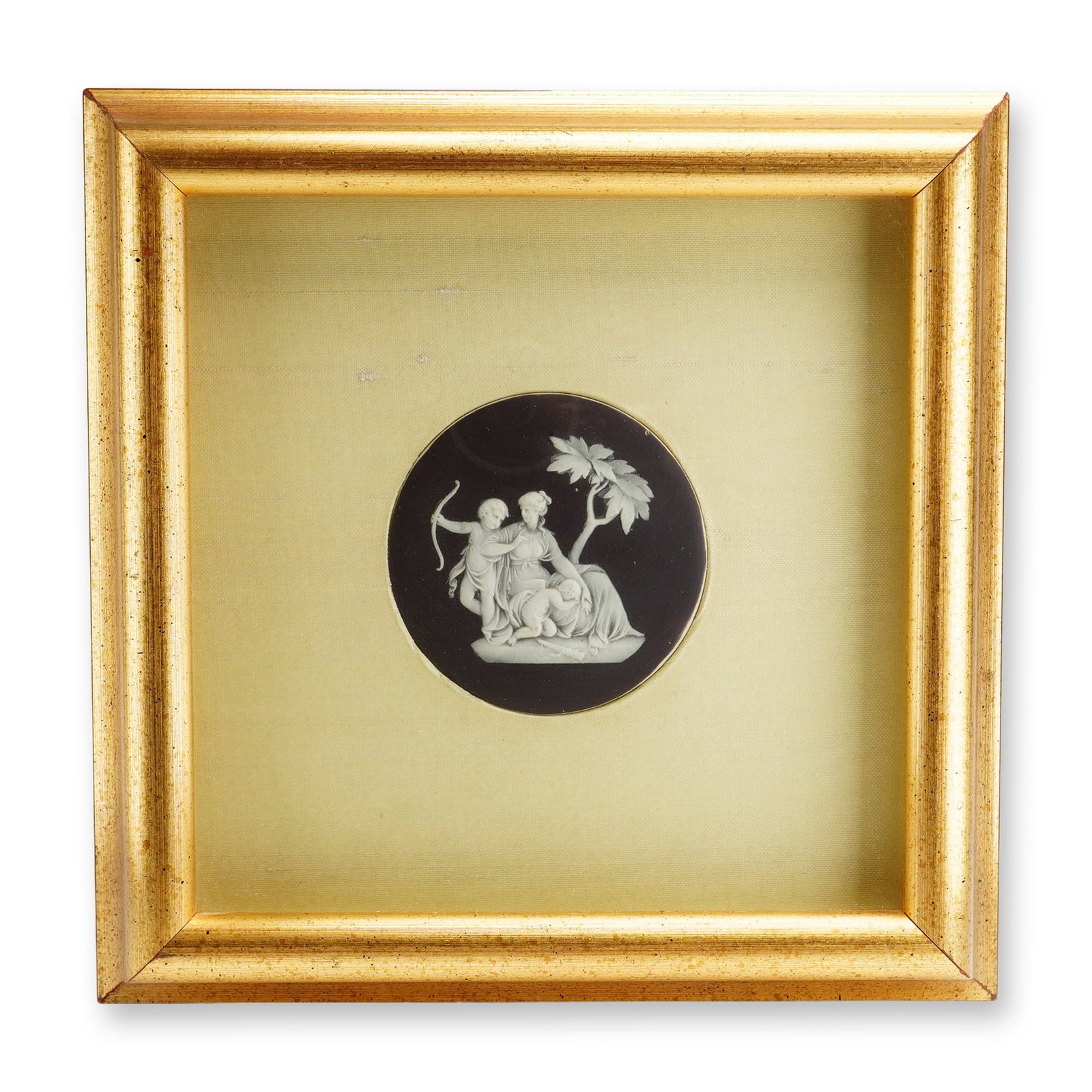 Wedgwood Neoclassical Black Jasperware Medallion: Wedgwood black jasperware circular medallion featuring a white sprigged bas-relief neoclassical scene of a seated female figure beneath a tree accompanied by two putti. Set within a square gilt-wood