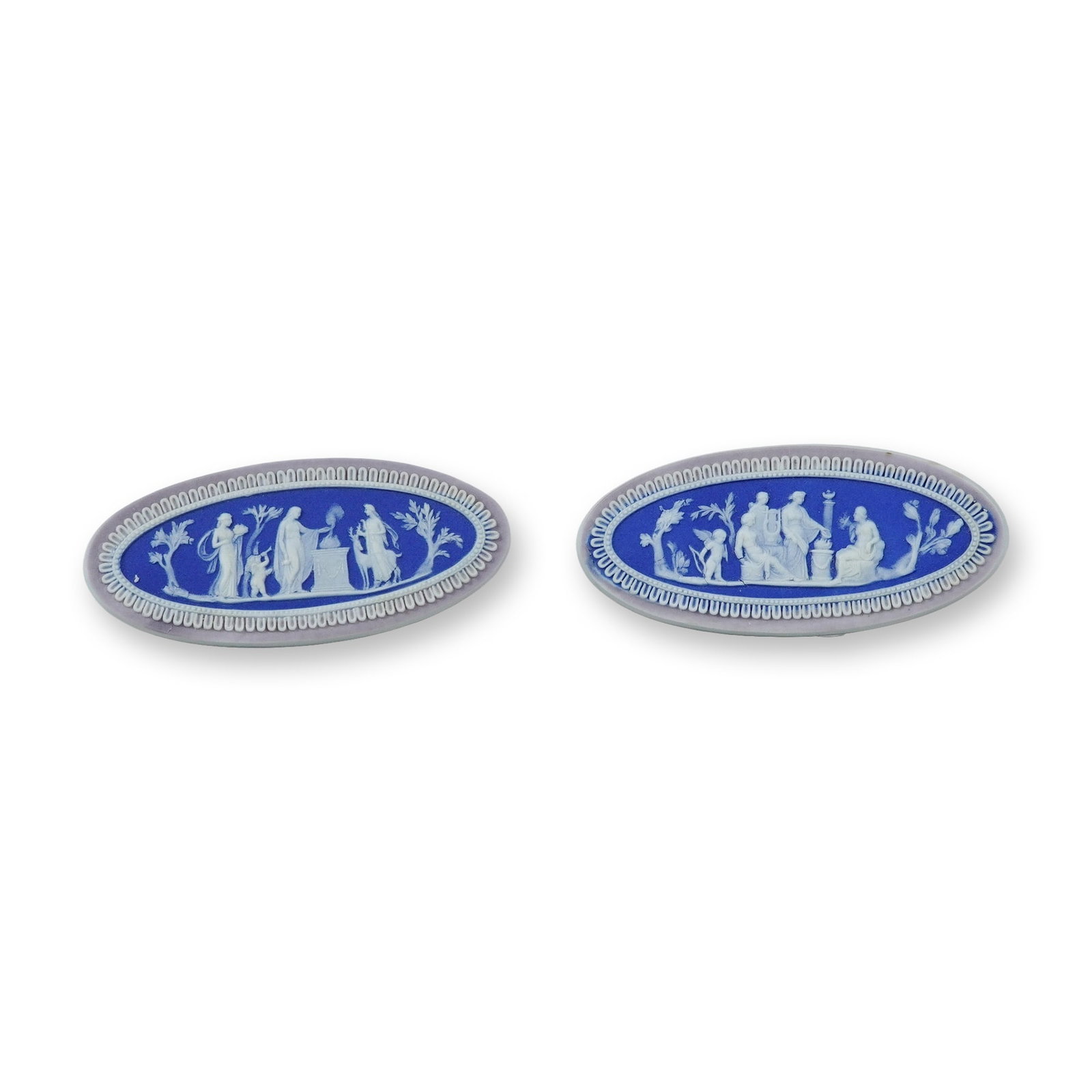 2pc Wedgwood Tricolor Jasperware Dip Medallions: Each piece is constructed of fine-grained unglazed stoneware with a vibrant blue jasper dip ground. The central scenes are executed in white sprigged bas-relief and are surrounded by a