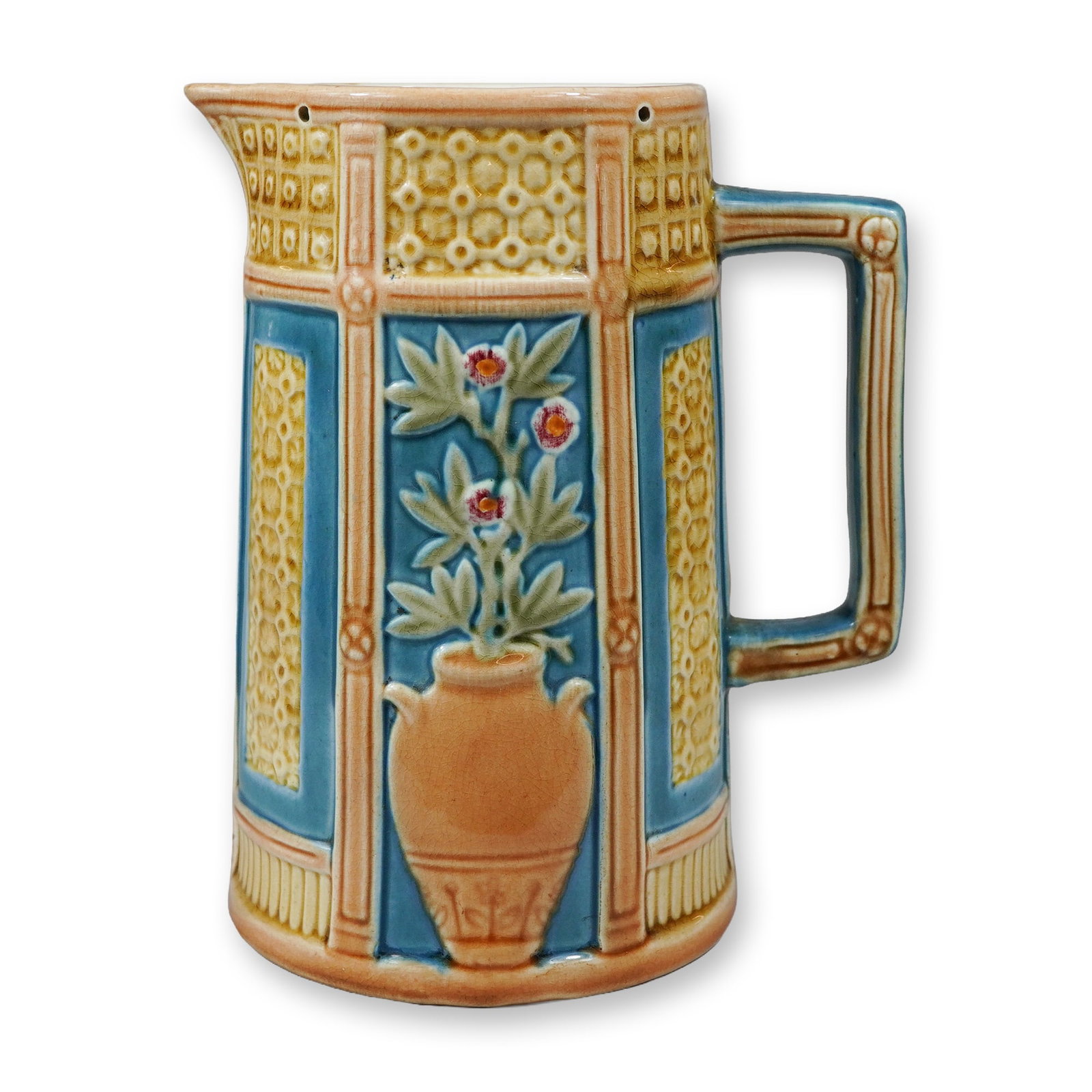 Wedgwood Majolica Relief-Decorated Pitcher: This Victorian era earthenware jug is a Wedgwood majolica relief-decorated pitcher, dated to approximately 1876. The vessel features a tall cylindrical form with a paneled exterior and a squared handl
