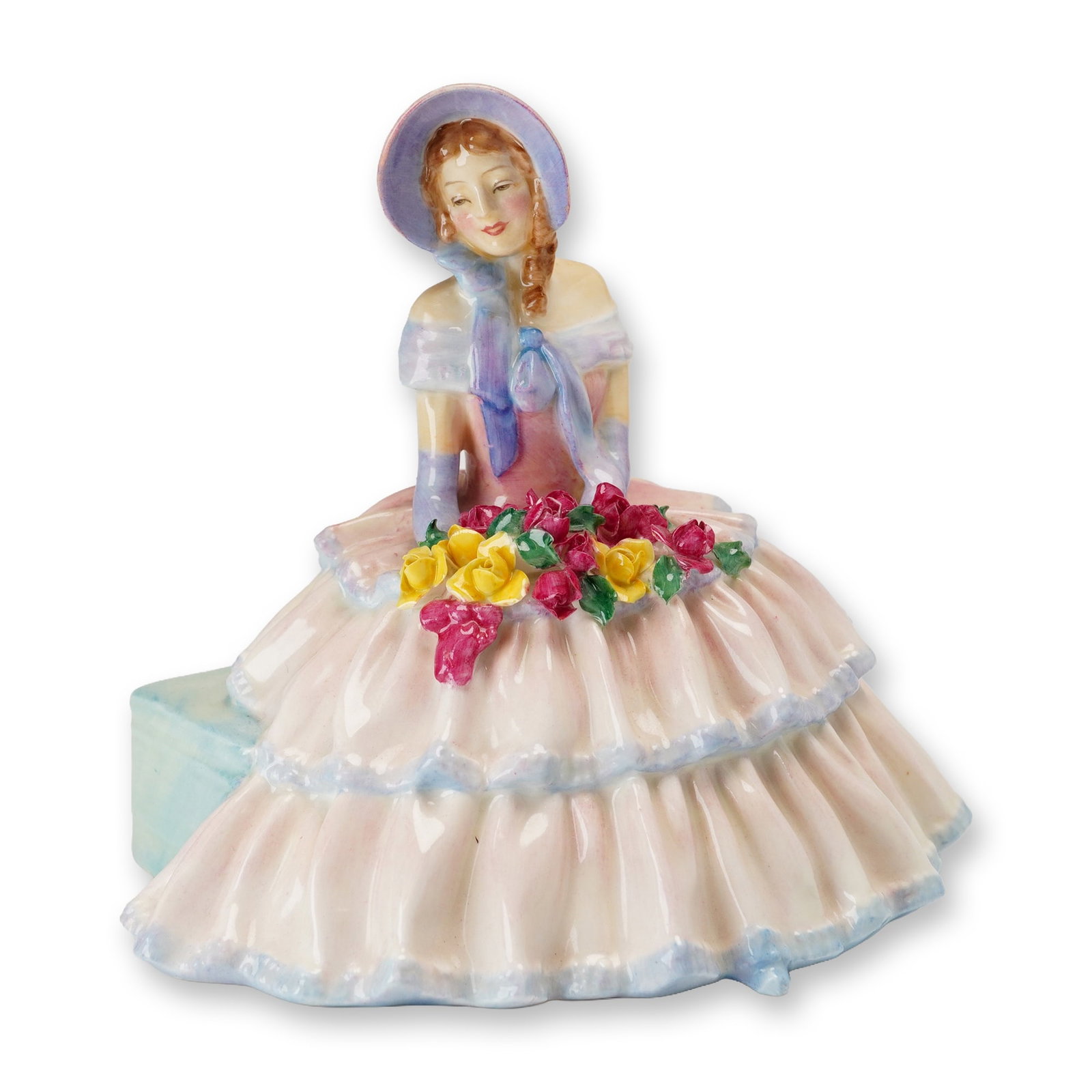 Royal Doulton Porcelain Figurine, Daydreams HN1732: Designed by Leslie Harradine. The glazed porcelain figure depicts a seated young woman in nineteenth-century style attire on a pale blue rectangular bench. She wears a tiered pink crinoline dress with