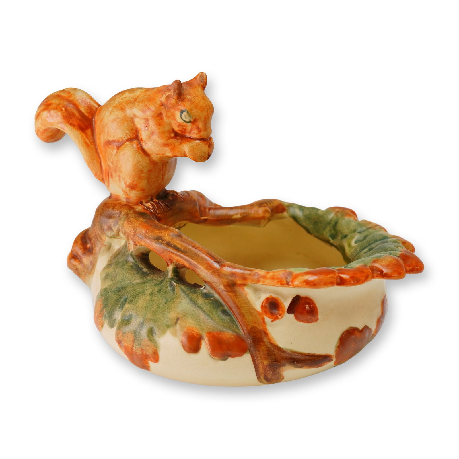 Weller Pottery Squirrel Nut Dish, Woodcraft: The piece is constructed of glazed ceramic and features a molded red-orange squirrel perched upon a brown branch that integrates into the rim. The cream-colored exterior is decorated with