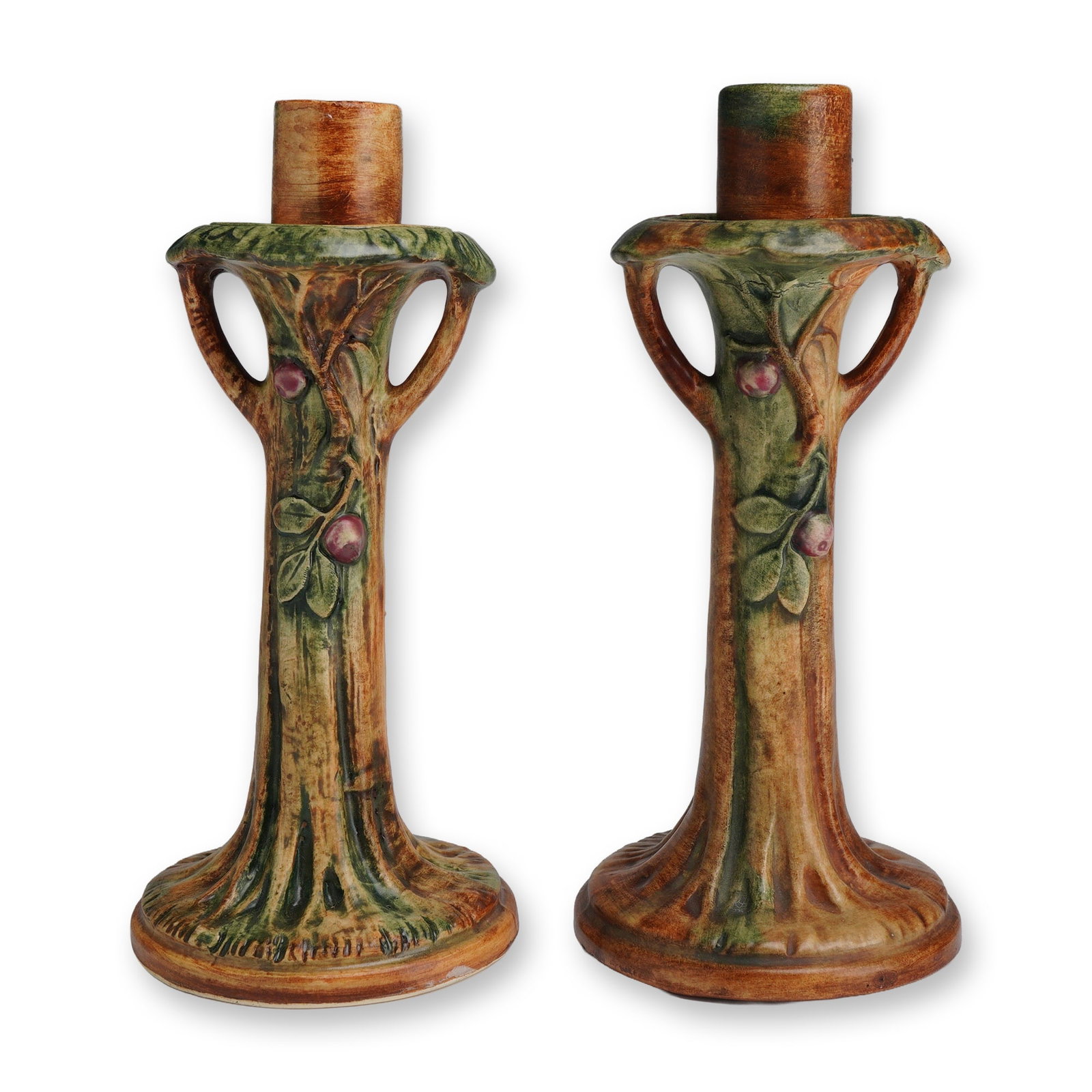 Pair of Weller Pottery Candle Holders, Woodcraft: Each candlestick holder is modeled in the form of a stylized tree trunk with spreading roots and branched nozzles. The naturalistic design features relief-molded foliage and purple fruit against a