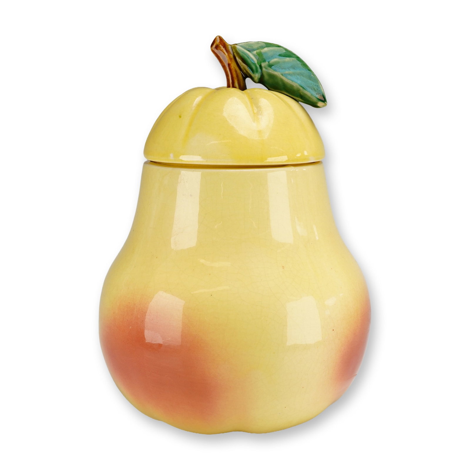 McCoy USA Pottery Pear Cookie Jar: A vintage McCoy Pottery pear cookie jar with lid of glazed ceramic construction. The vessel is modeled in the form of a pear with a high-gloss, pale yellow glaze featuring an orange-red blush. The mat