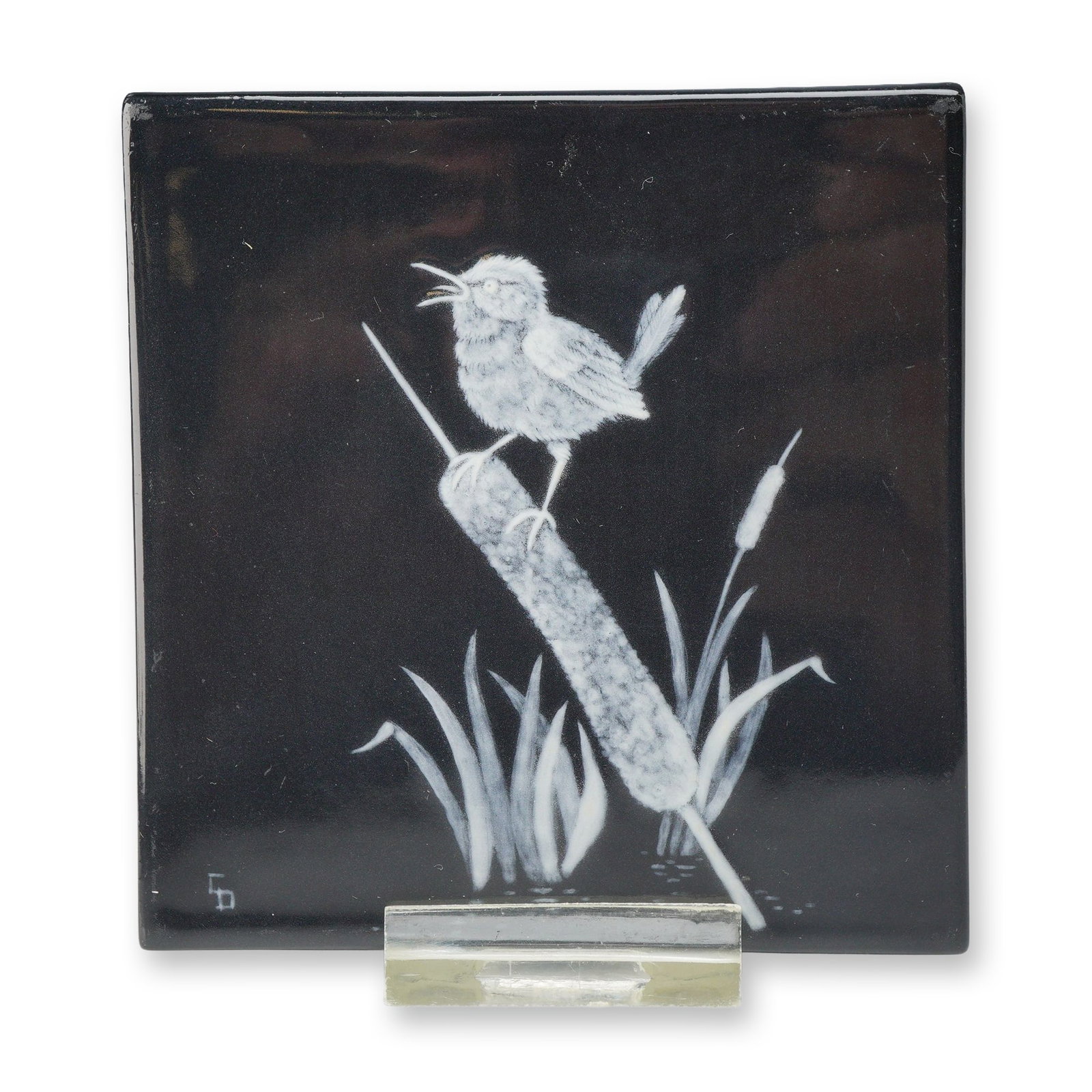 Wedgwood Glazed Black Basalt Trial Tile with Bird and Bulrush: A square Wedgwood trial tile featuring a translucent white slip decoration against a high-gloss black glazed ground. The design depicts a small bird with an open beak, perched on a bulrush or cattail 