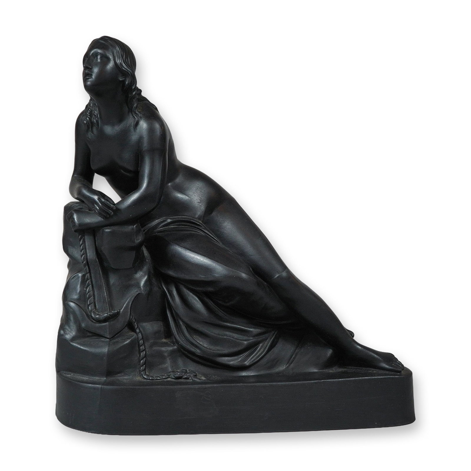 Wedgwood Black Basalt Figure of Hope: A Wedgwood black basalt figure depicting the personification of Hope, executed in the Neoclassical style. The semi-draped female figure is posed reclining against a rocky outcropping, her arms resting