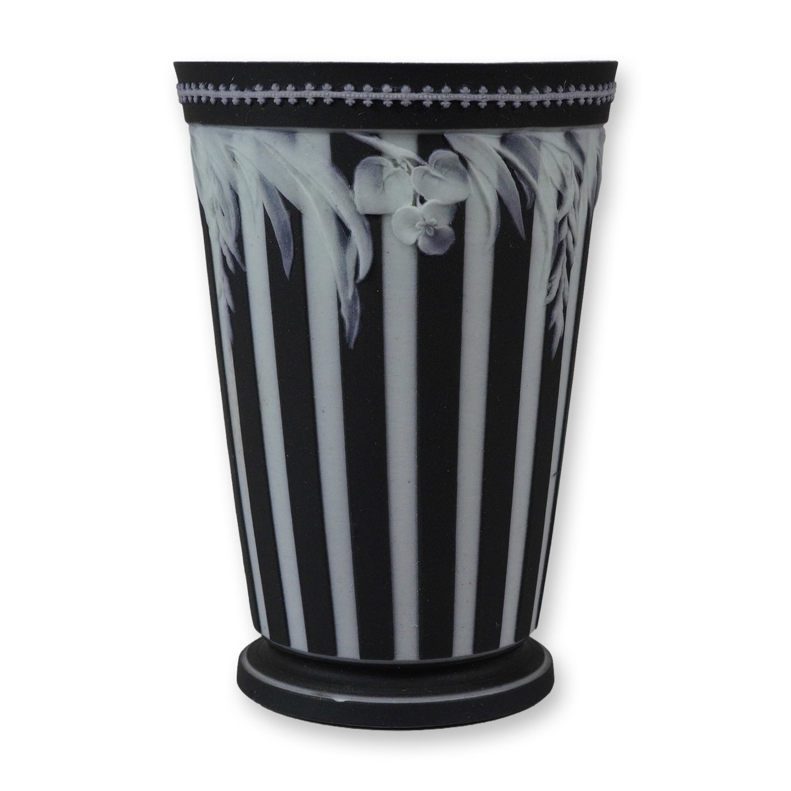 Wedgwood Black and White Engine Turned Jasperware Beaker: A tapered cylindrical jasperware beaker featuring alternating vertical stripes of black and white. This striped effect is achieved through engine turning, a technique characteristic of specific Wedgwo