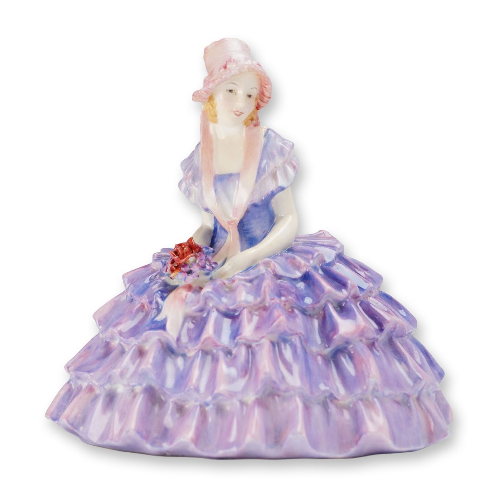 Royal Doulton Porcelain Figurine, Chloe HN1479: Designed by Leslie Harradine. The figure depicts a seated woman in an elaborate tiered and ruffled skirt featuring variegated lavender, purple, and pink glazes. The subject wears a blue bodice with ru