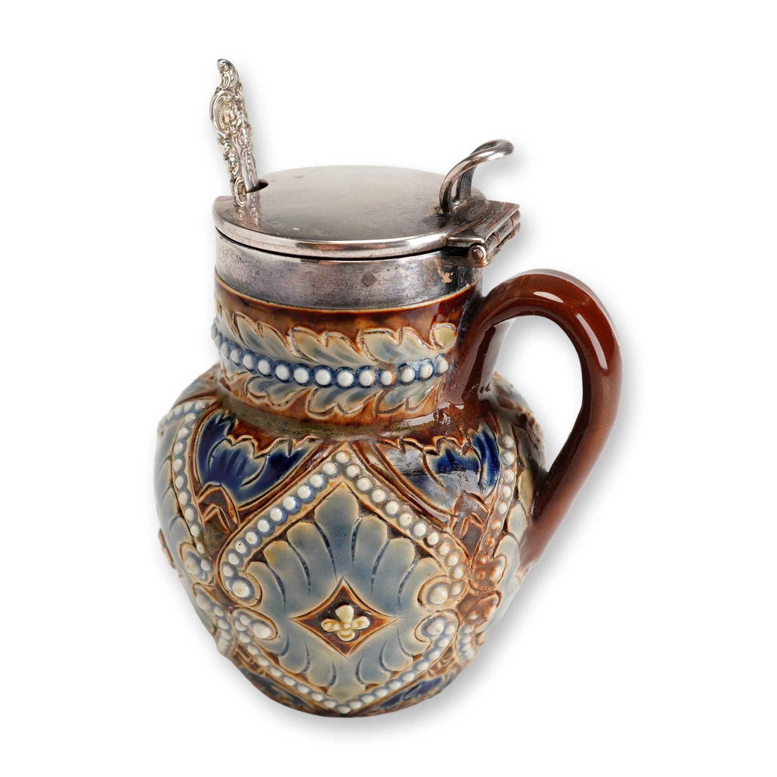 Doulton Lambeth Stoneware Mustard Pot with Wallace Sterling Silver Spoon: A small bowl in blue, white, and brown tones, decorated with an Art Nouveau floral motif and accented by white beaded relief detailing. The piece features a sterling silver rim and lid, and Wallace st