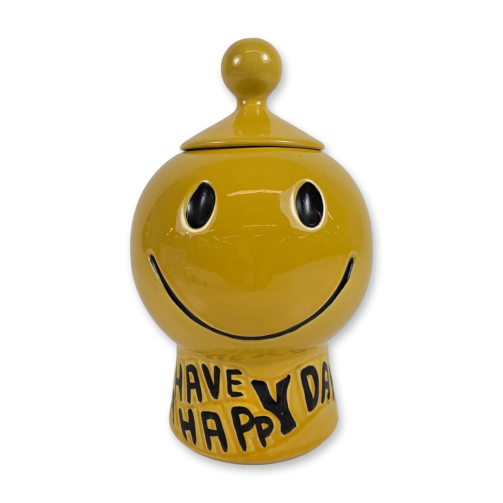 McCoy Ceramic Smiley Face Cookie Jar: The spherical body features a classic smiley face with recessed eyes and mouth accented in black. The jar sits on a flared pedestal base with the relief-molded phrase HAVE A HAPPY DAY, also finished w