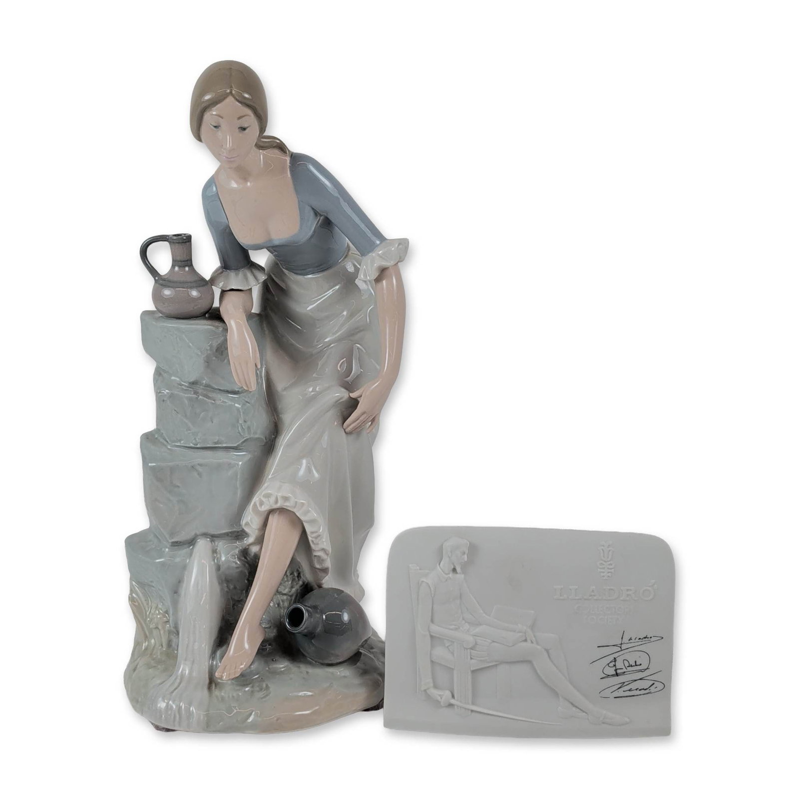 Two-Piece Lladro and NAO Porcelain Collection, Sculpture and Don Quixote Plaque: Spain, late 20th century. Glazed porcelain sculpture and commemorative plaque. The NAO by Lladro figurine, depicts a young woman in rustic attire leaning against a stone structure with water pitchers.