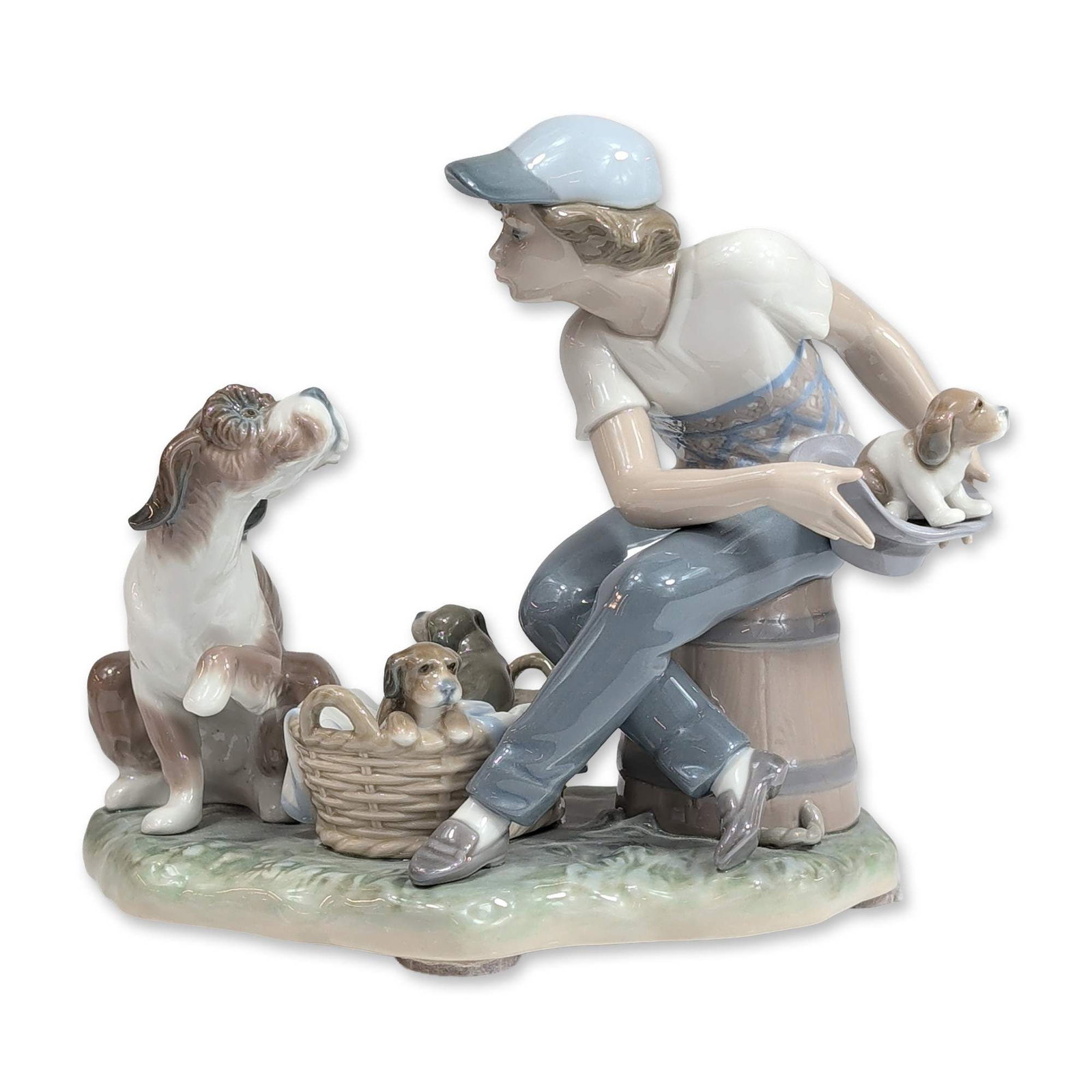 Lladro Porcelain Figurine, This One's Mine 1005376: Lladro. Glazed porcelain figurine titled This One's Mine, model number 5376. The scene depicts a young boy wearing a cap and a geometric patterned sweater seated on a barrel, holding a puppy inside a 