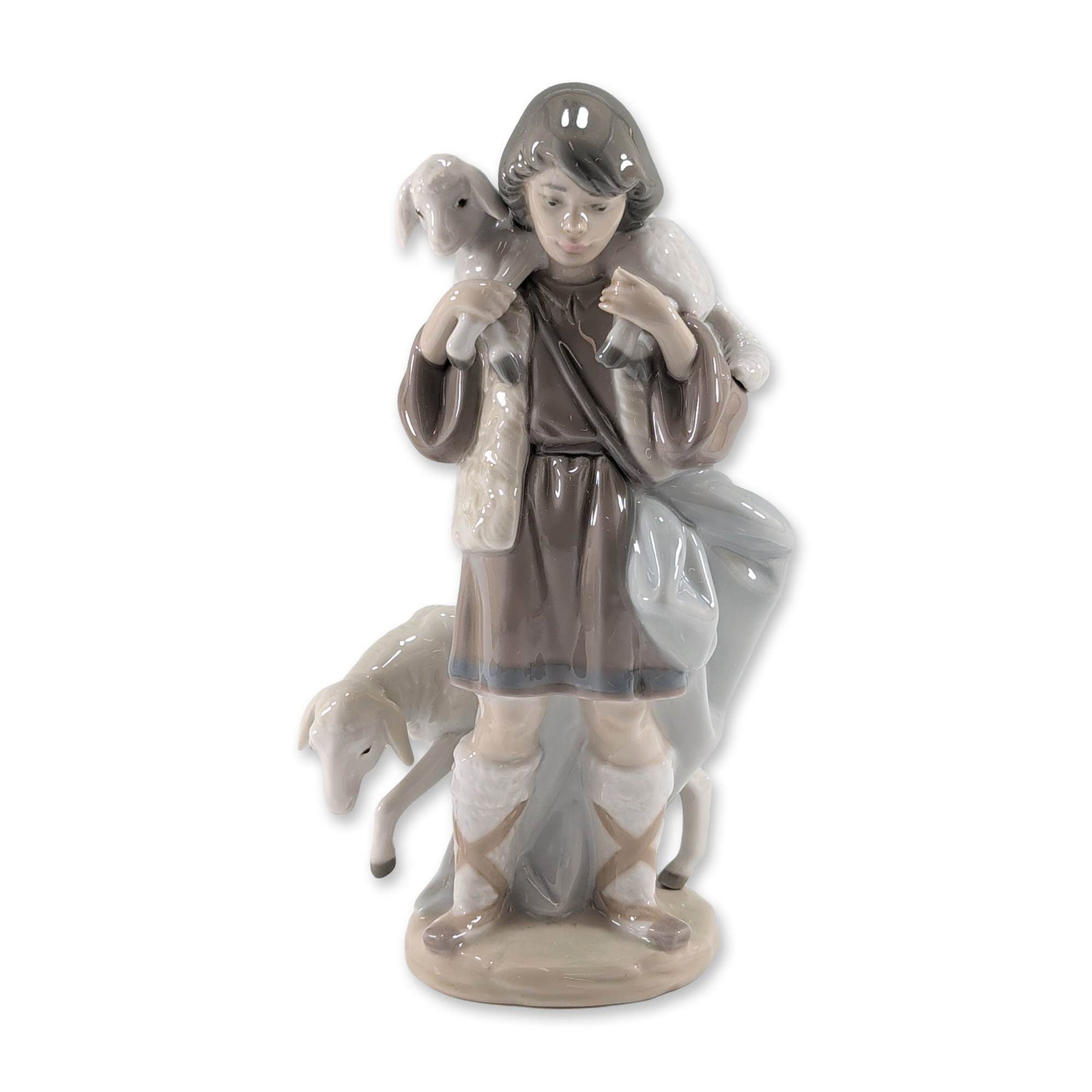 Lladro Shepherd Boy Porcelain Figurine 5485: Lladro Spanish glazed porcelain figurine, model 5485, titled Shepherd Boy. This piece depicts a young shepherd in traditional rustic attire carrying a lamb across his shoulders while a second sheep st