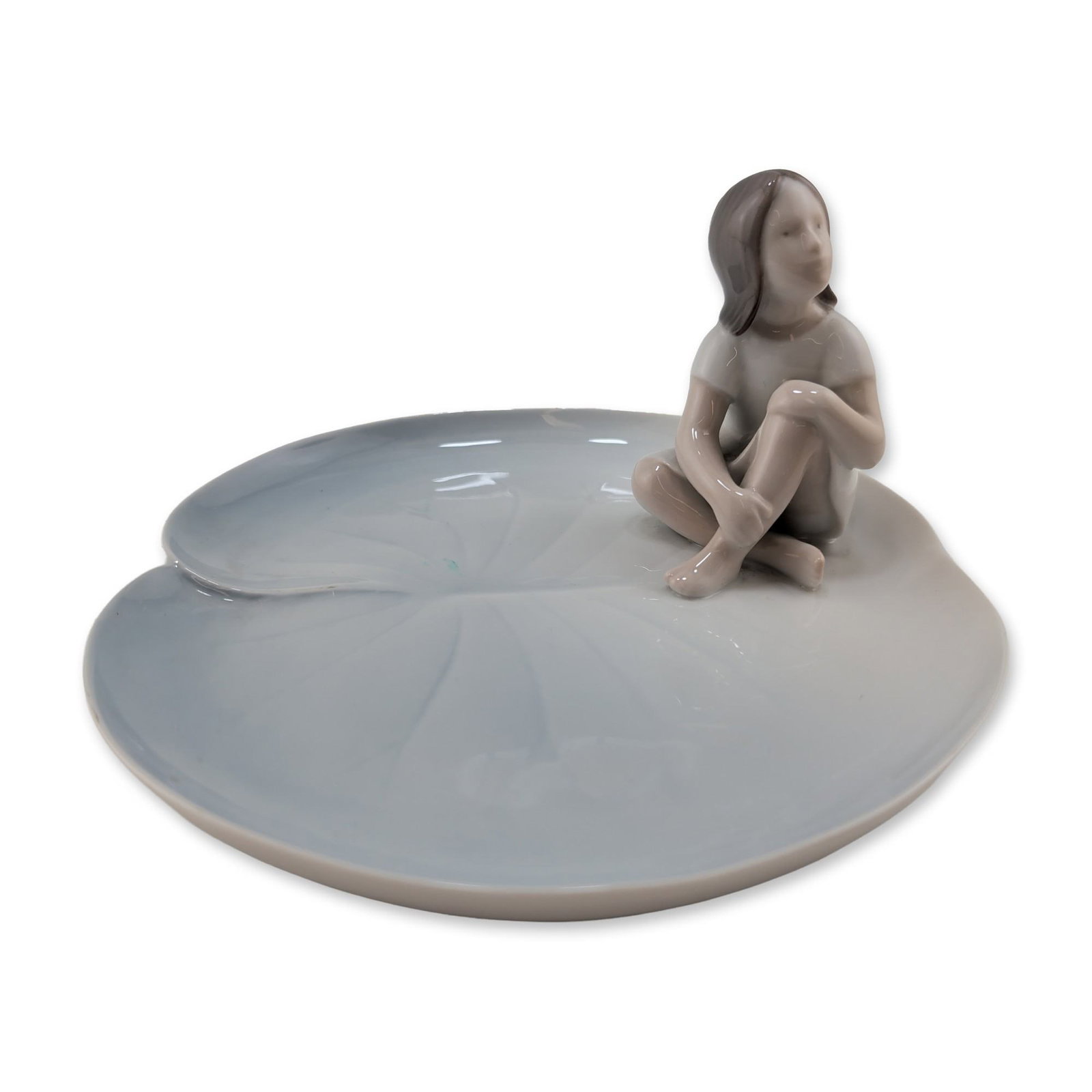 Bing and Grondahl Danish Porcelain Thumbelina on Lily Pad: Bing and Grondahl porcelain vide-poche or decorative dish, model number 2378. The piece features a stylized figure of a child in a crouched position perched upon the edge of a large lily pad leaf. The