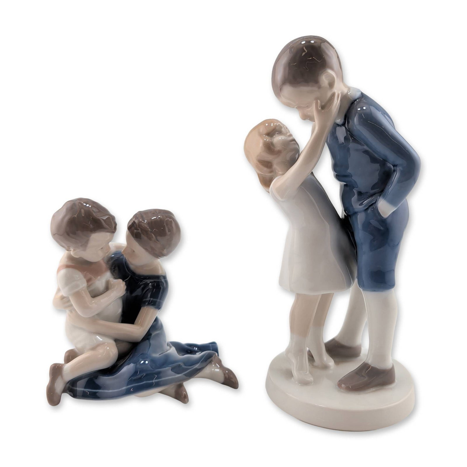 2pc Bing & Grondahl Danish Porcelain Figurines: Pair of Bing & Grondahl glazed porcelain figurines, produced in Denmark. The lot features two distinct vignettes of children. The first figurine, model number 1781, depicts a standing boy in a blue su