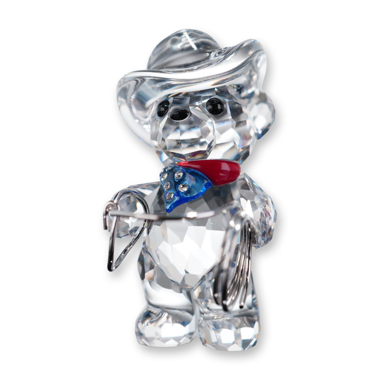 Swarovski Crystal Figurine, Kris Bear Johnny American Cowboy: Swarovski. Kris Bear Jhonny figurine in faceted lead crystal, featuring a molded cowboy hat and a red and blue enameled bandana with inset crystal accents. The figure holds a silver-tone metal lasso. 