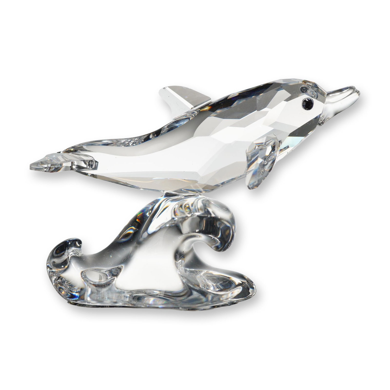 Swarovski Crystal Figurine, Baby Dolphin on Wave: Swarovski crystal figurine of a baby dolphin on a wave. The figure features a faceted clear crystal dolphin in a leaping pose over a smooth, molded clear crystal wave base with black crystal eyes. Aci