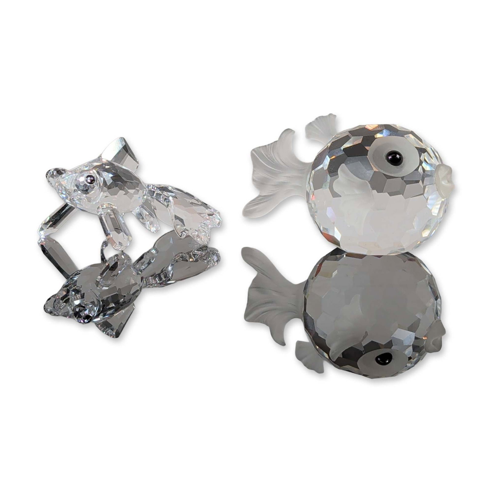 Two Swarovski Crystal Fish Figurines, Blowfish and Telescope: Group of two faceted crystal figurines featuring marine subjects. Includes one figurine of two leaping fish in a circular formation and one figurine of two rounded pufferfish. Crafted in clear lead cr