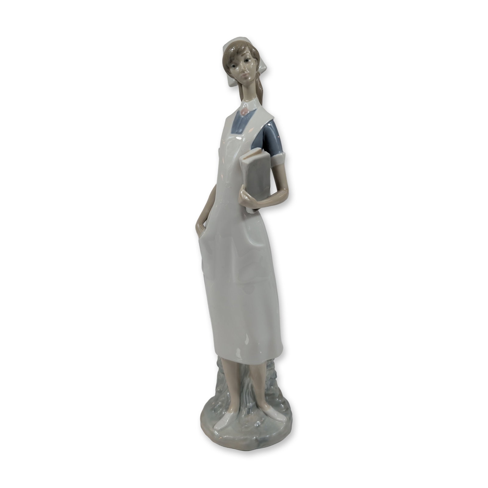Lladro Spanish Glazed Porcelain Nurse 4603 Figurine: Lladro, Spain. Glazed porcelain figurine titled Nurse, model number 4603, designed by sculptor Salvador Furio. The figure is depicted in a traditional nurse uniform with a white cap and apron over a b