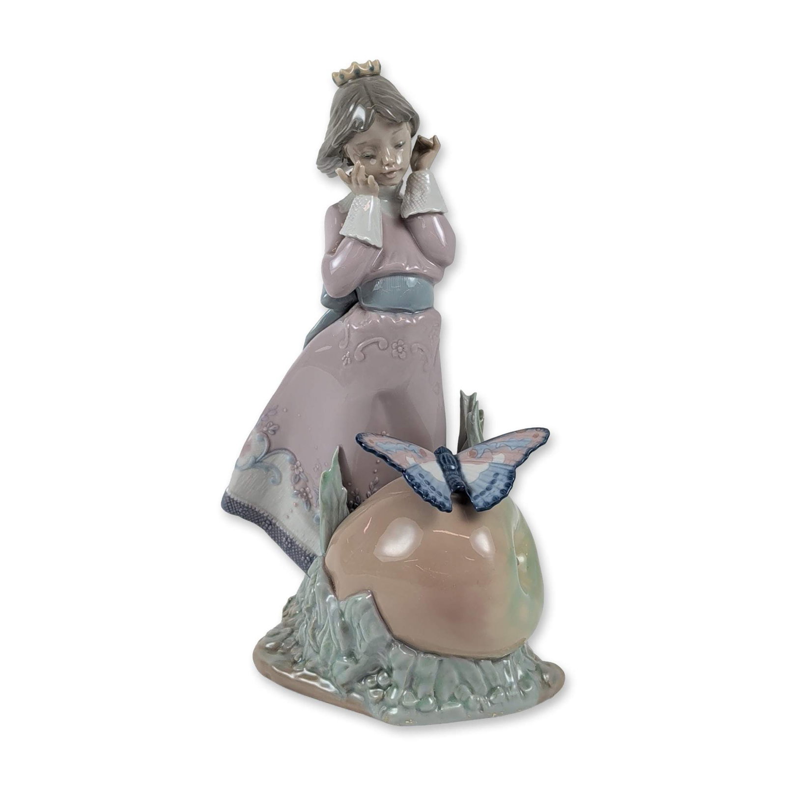 Lladro Porcelain Figurine, Land of the Giants 1005716: Model 5716 is a glazed porcelain figurine featuring a young girl in a crown and a long gown decorated with floral reliefs, leaning forward to admire a large butterfly perched atop an apple on a textur