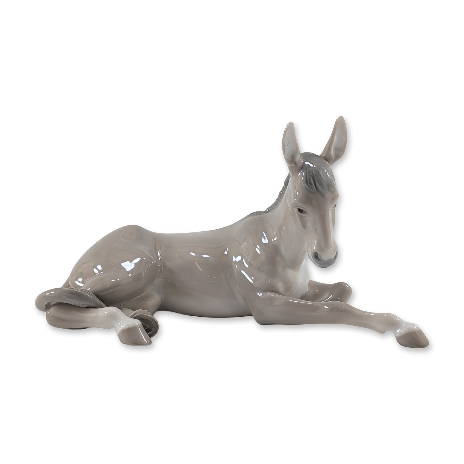 Lladro Spanish Glazed Porcelain Donkey Figurine: Lladro (Spain). Glazed porcelain figurine titled Donkey, model number 5483, designed by Juan Huerta. The figure depicts a reclining young donkey with its head turned over its right shoulder, rendered 