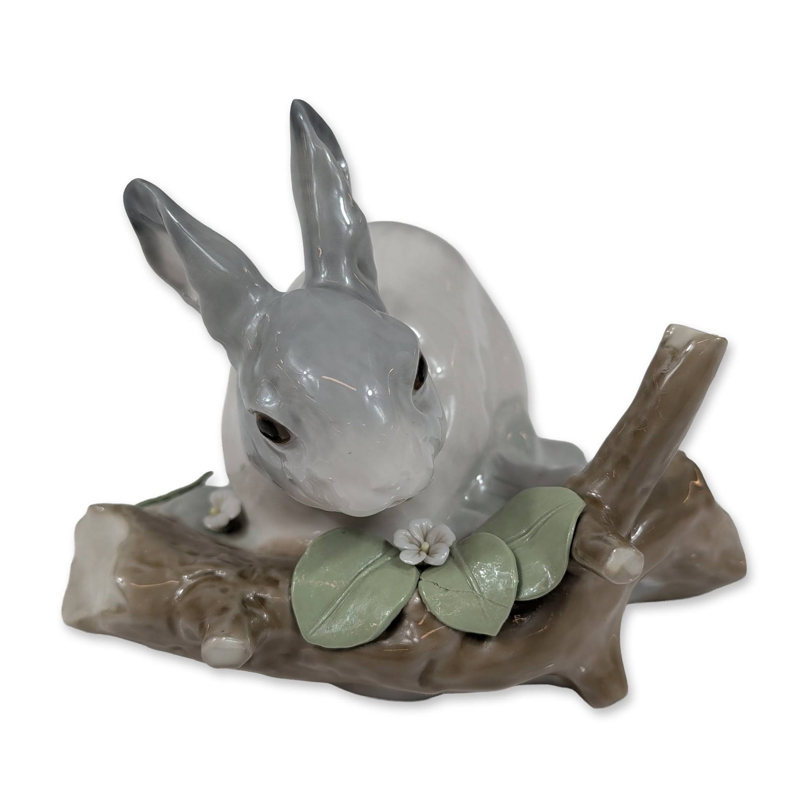Lladro Spanish Glazed Porcelain Rabbit Eating 4773 Figurine: Lladro (Spain) glazed porcelain figurine, model number 4773, titled Rabbit Eating. The piece depicts a grey and white rabbit resting beside a brown tree stump decorated with three green leaves and two