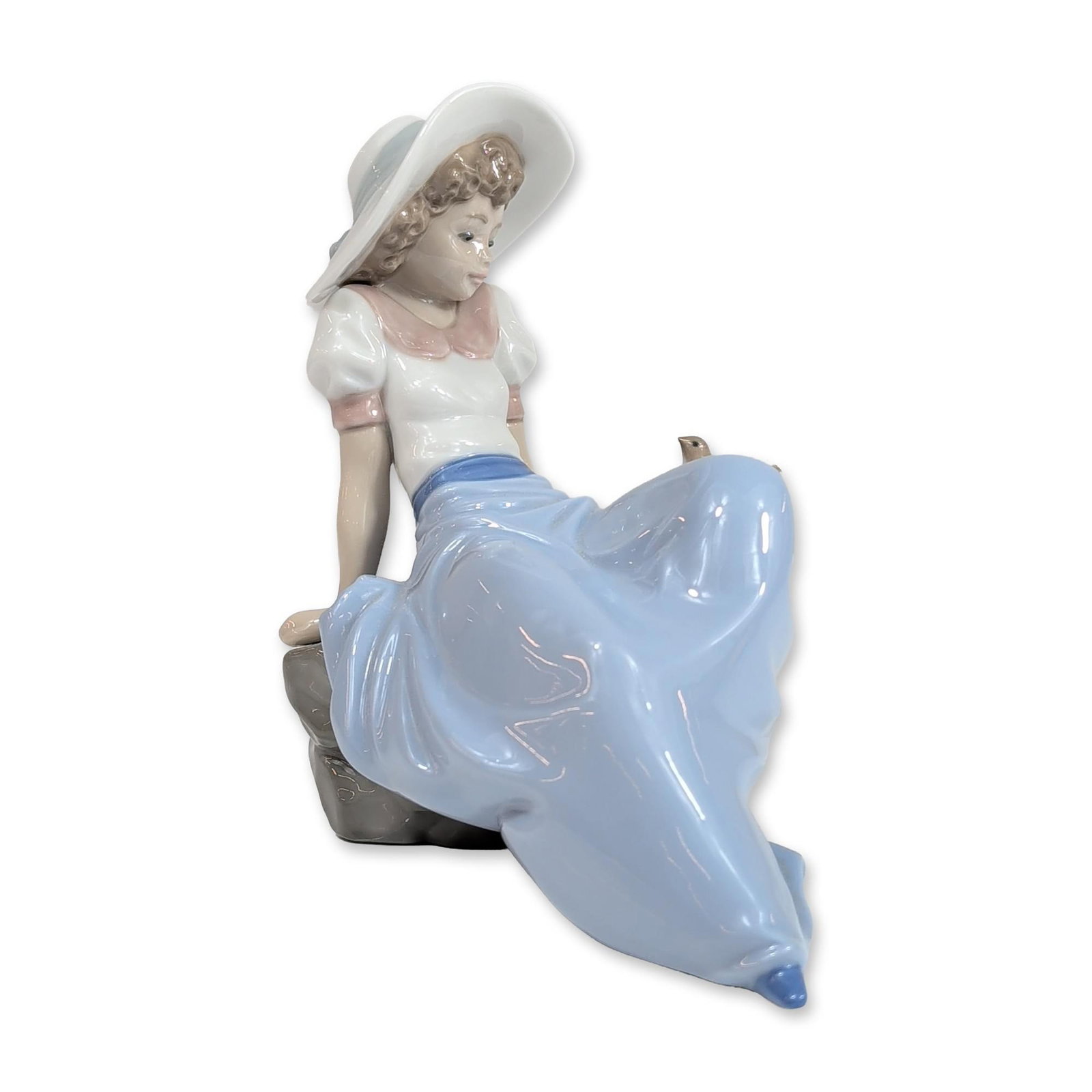 Nao by Lladro Porcelain Figurine, Girl Listening to the Bird's Song: Nao by Lladro, model 1042. Glazed porcelain figurine titled Girl Listening to Bird Song, depicting a young woman wearing a wide-brimmed white sun hat with a light blue ribbon, a white blouse with pink