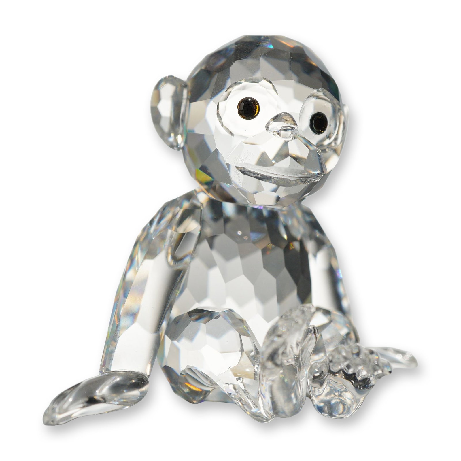 Swarovski Crystal Sitting Chimpanzee Figurine: Swarovski lead crystal figurine of a sitting chimpanzee, featuring a fully faceted head and body with applied ears, hands, and feet, and dark brown crystal eyes. Marked on the underside with the acid-
