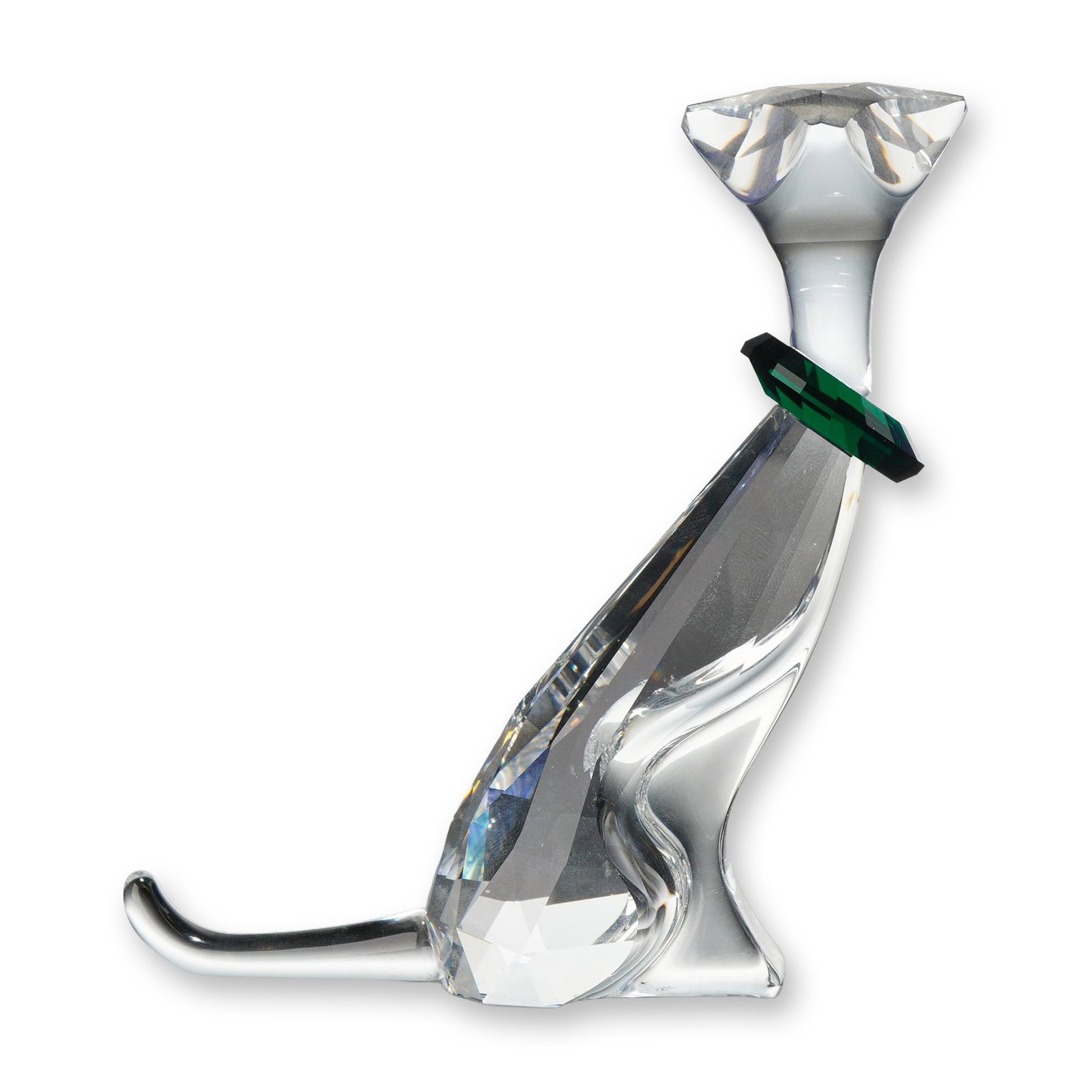 Swarovski Crystal Figurine, The Cat with Box: This clear faceted and smooth crystal piece depicts a stylized seated cat with a tall neck and pointed ears, accented by a separate emerald, green faceted crystal collar. The underside of the faceted 