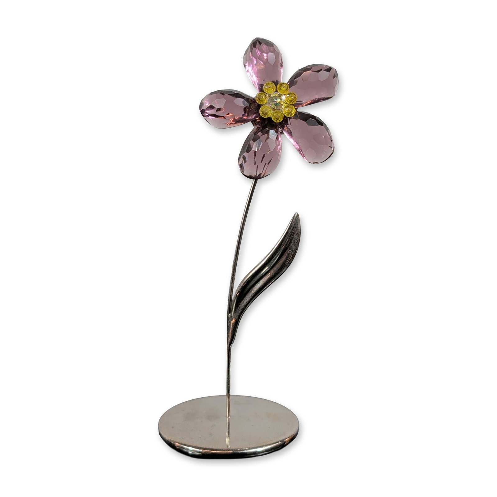 Swarovski Crystal Paradise Deoli Amethyst Flower Figurine: Deoli Amethyst flower figurine from the Crystal Paradise collection, featuring five faceted amethyst-colored crystal petals surrounding a central cluster of yellow crystal chatons. The bloom is mounte