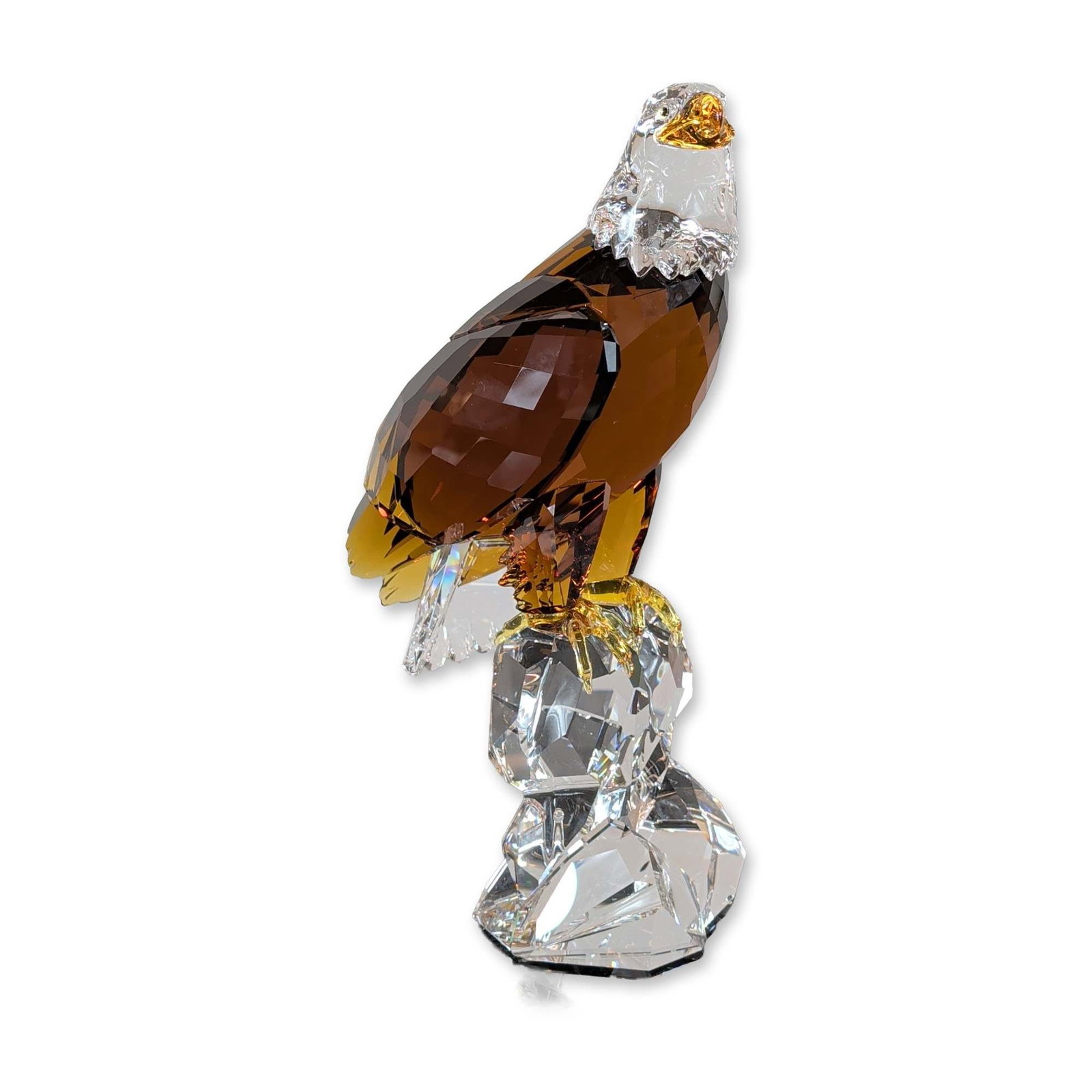 Swarovski 2011 Limited Edition Crystal Bald Eagle Scupture: 2011 Swarovski. Limited edition bald eagle sculpture in faceted crystal, depicting a bird in flight with a clear faceted head and translucent amber body. The figure is mounted to a multi-faceted clear