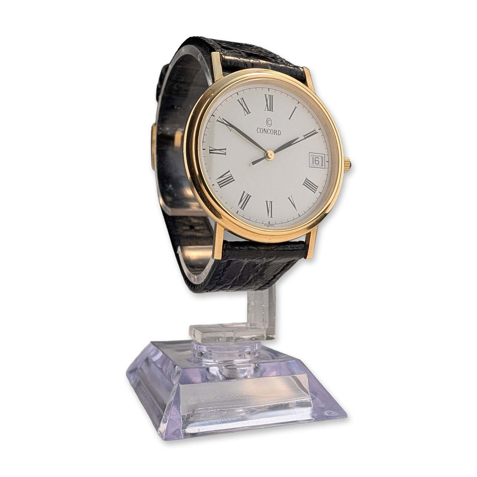 Concord 14K Yellow Gold Classic Dress Watch: Concord classic dress watch in 14k yellow gold, featuring a white dial with printed black Roman numeral hour markers, a date aperture at the 3 o clock position, and an inner minute track. The slim cir