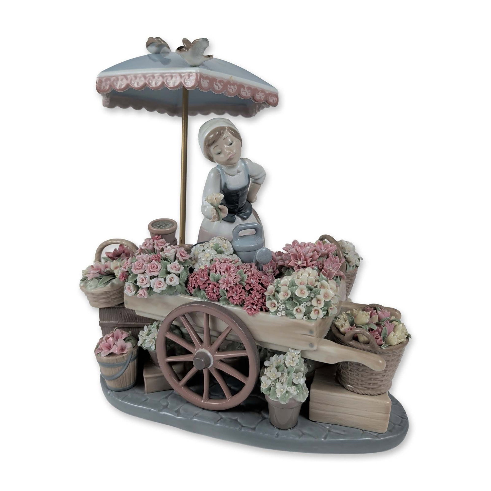 Lladro Porcelain Figurine, Flowers of the Season 01001454: Flowers of the Season (model 1454) is a glazed porcelain figurine designed by Jose Puche. It depicts a female vendor in traditional clothing standing beside a wooden-style cart filled with baskets of 